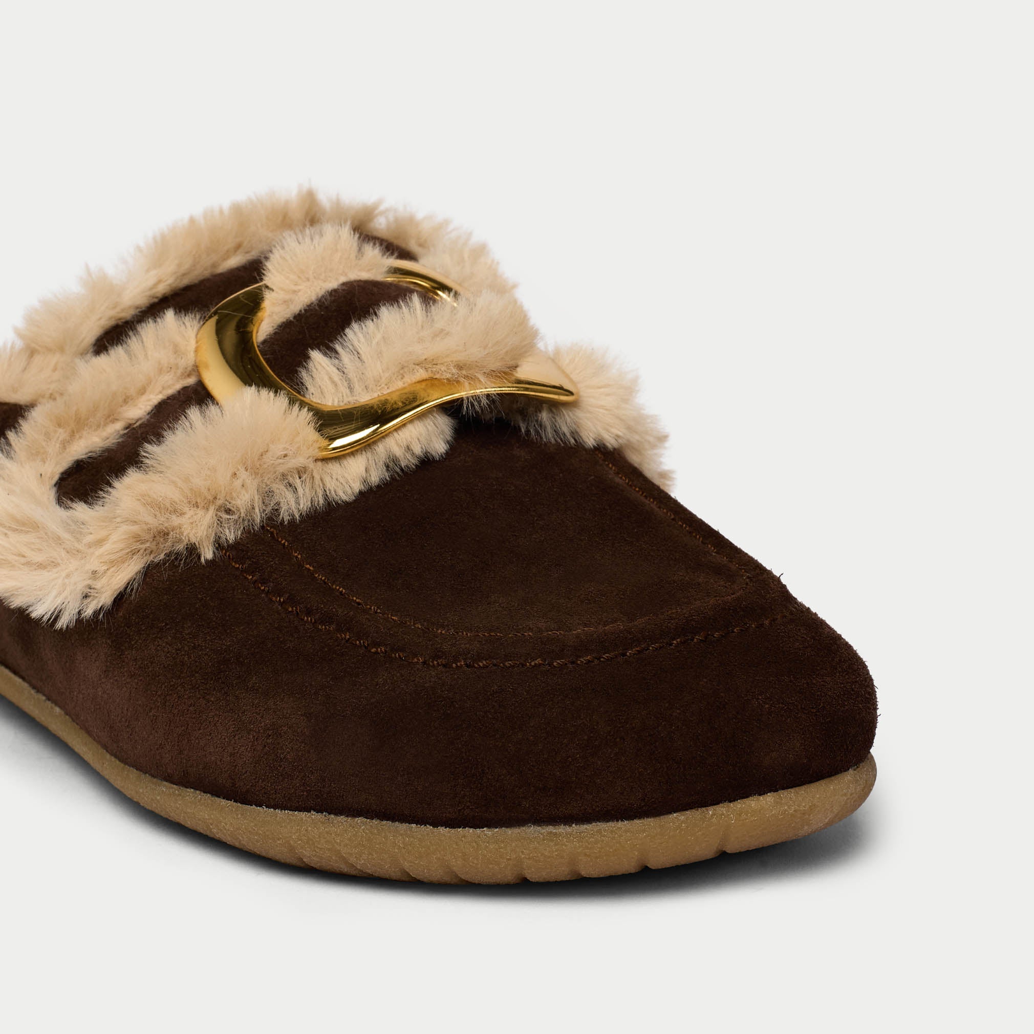Brown slipper with beige fur lining and gold buckle on a light gray background