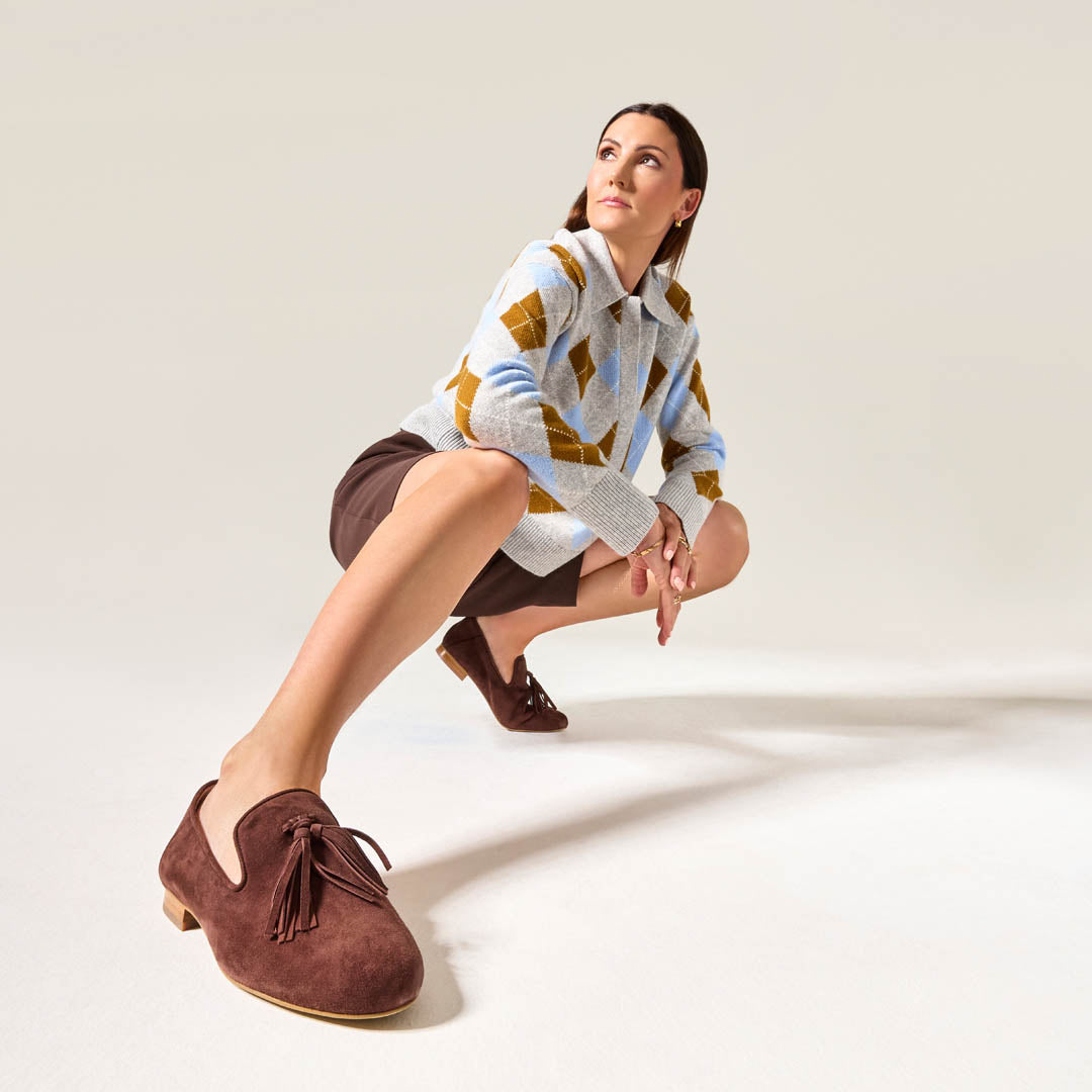 Woman wearing a patterned sweater and brown shoes on a plain background