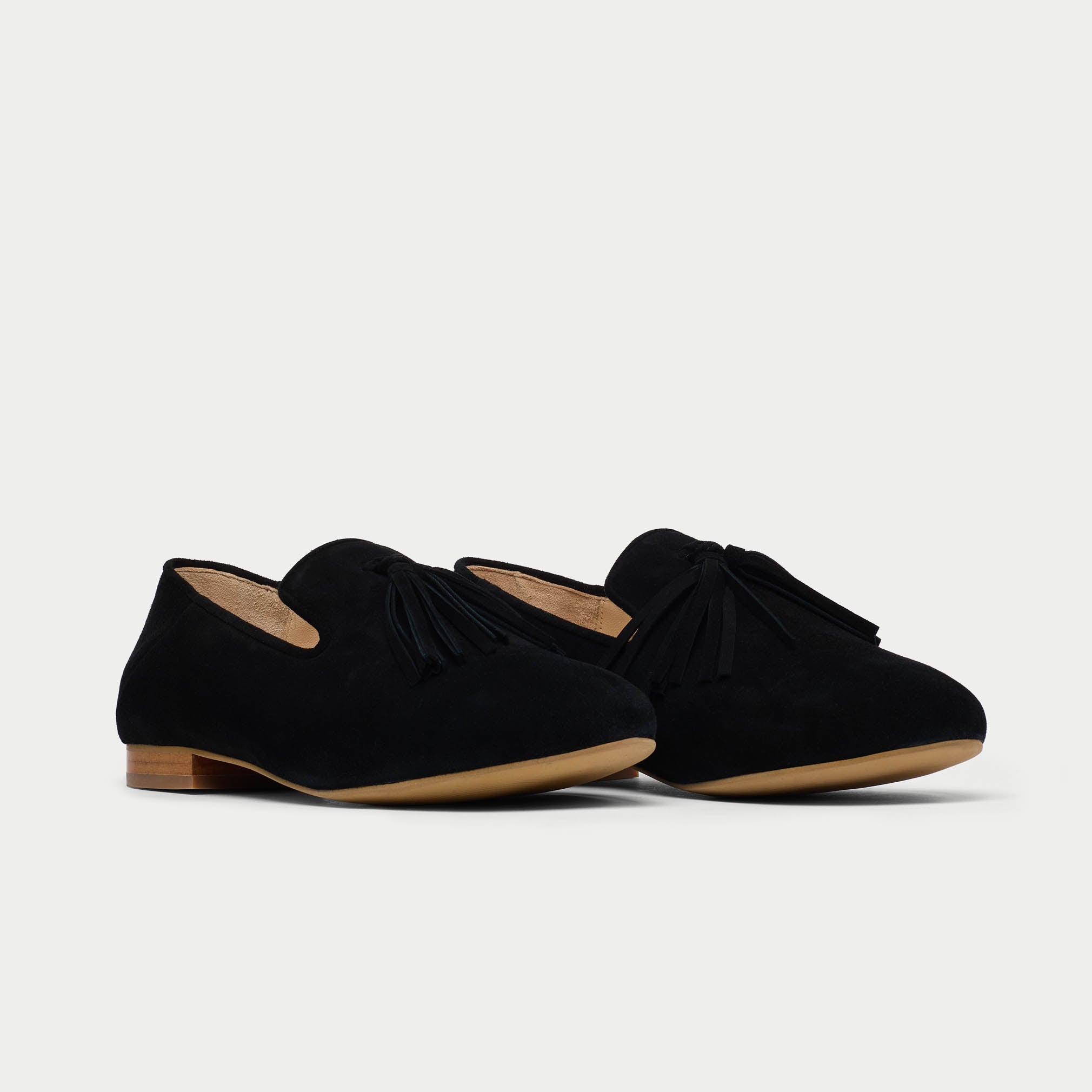 Pair of black loafers with bow details on a light gray background