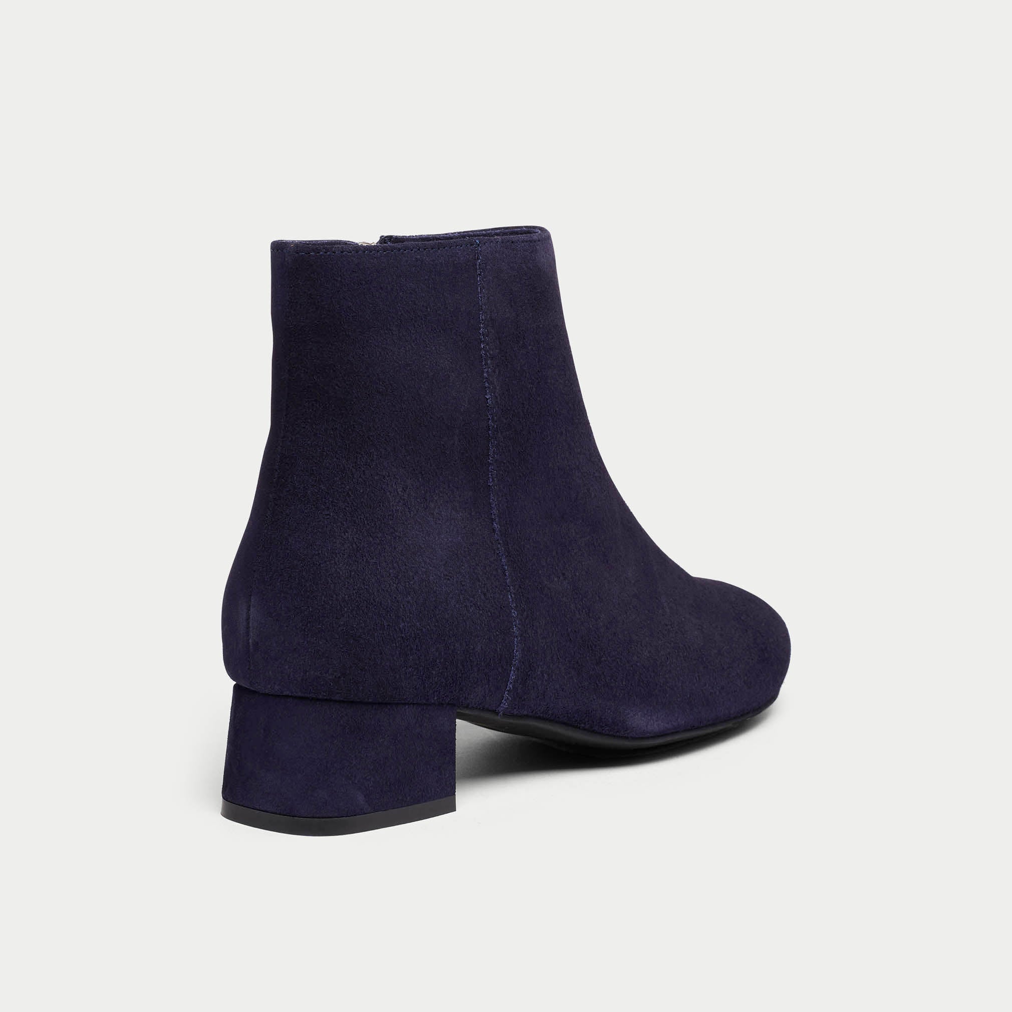 Navy blue ankle boots on a light gray background