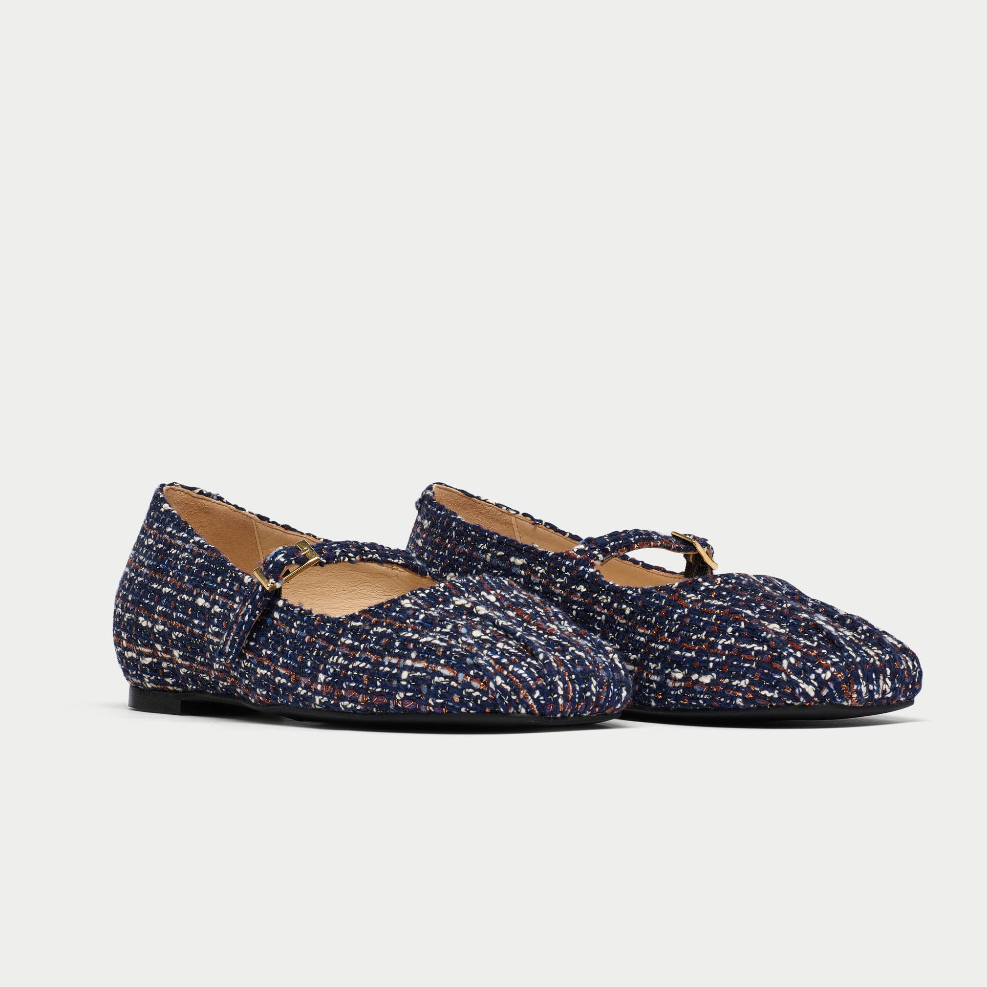 Pair of navy blue tweed shoes with a strap on a light gray background