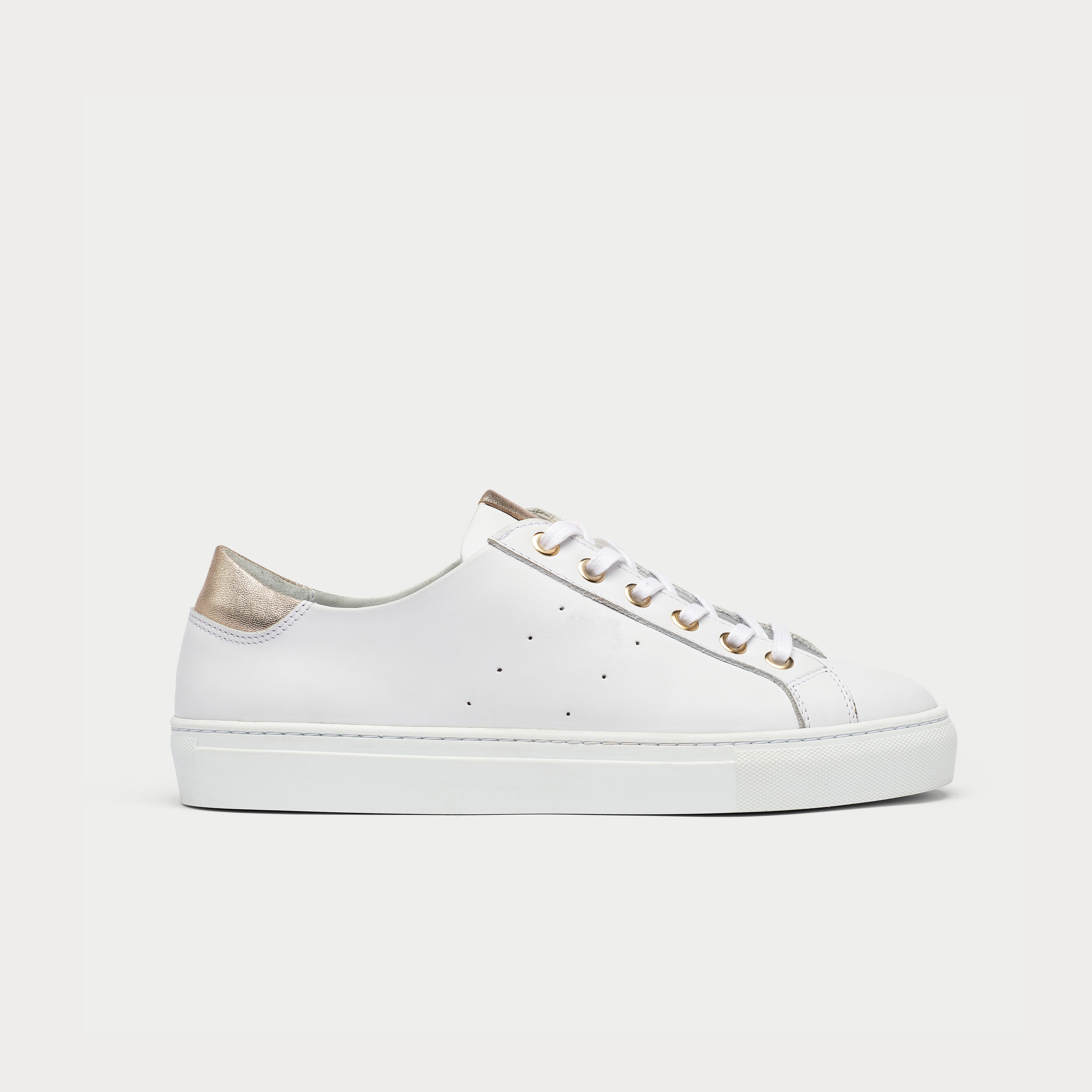 A white leather sneaker with champagne accents, featuring a wide fit and a removable molded footbed.