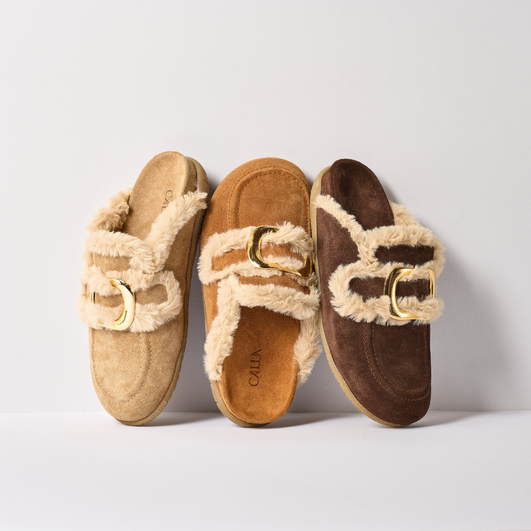 Three pairs of slippers with fur trim and gold buckles on a light background