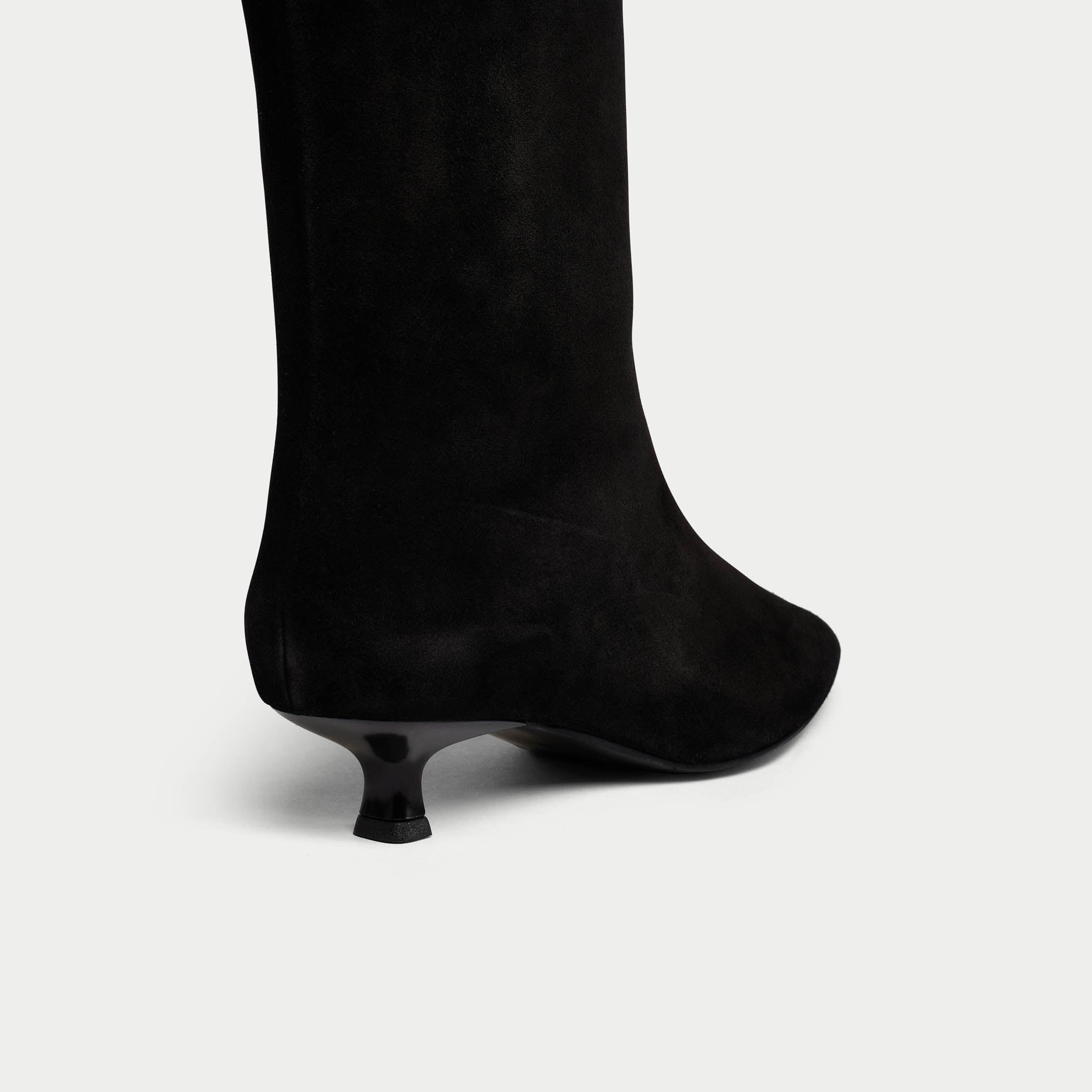 Black knee-high boot with a thin heel on a light gray background