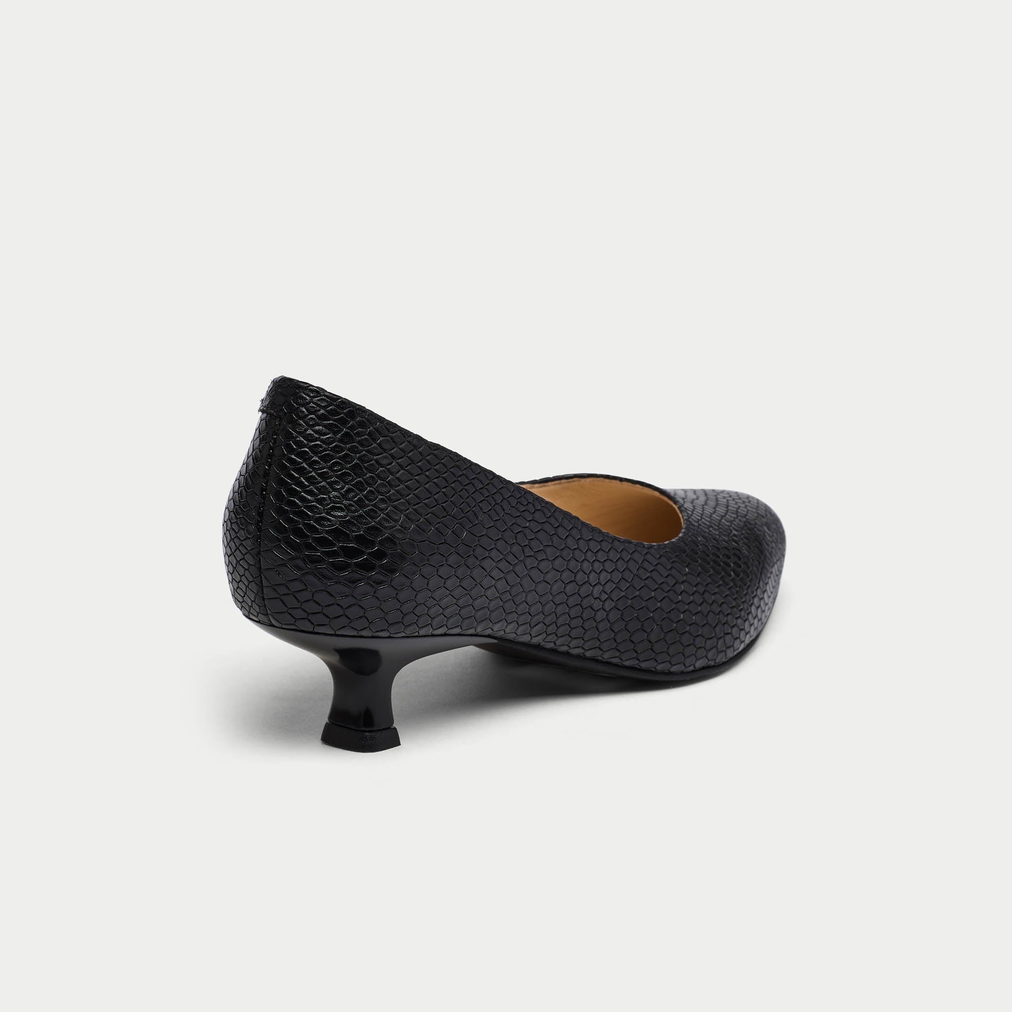 Black textured low heel shoe on a light gray background