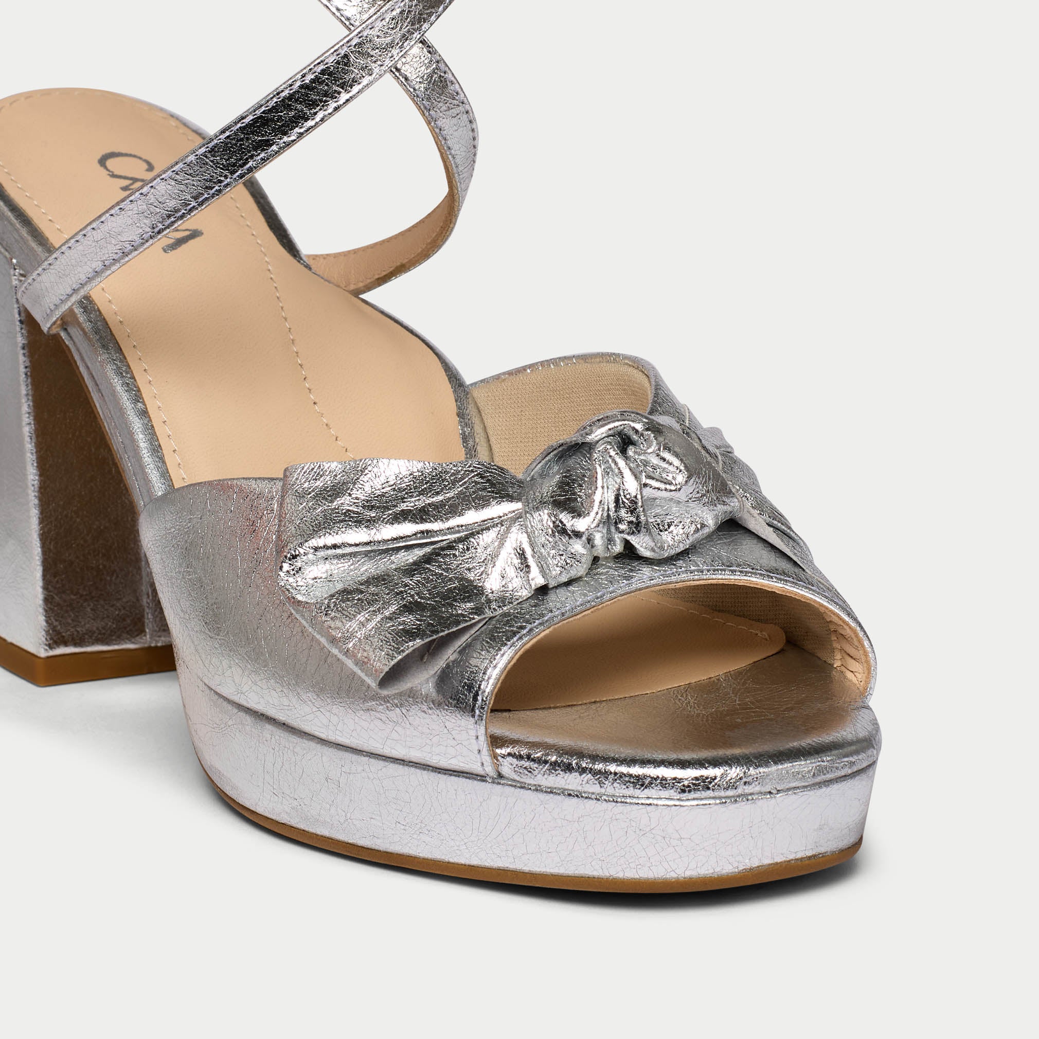 Silver platform sandal with a bow on a white background