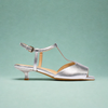 Silver sandal with open toe and kitten heel on a light green background
