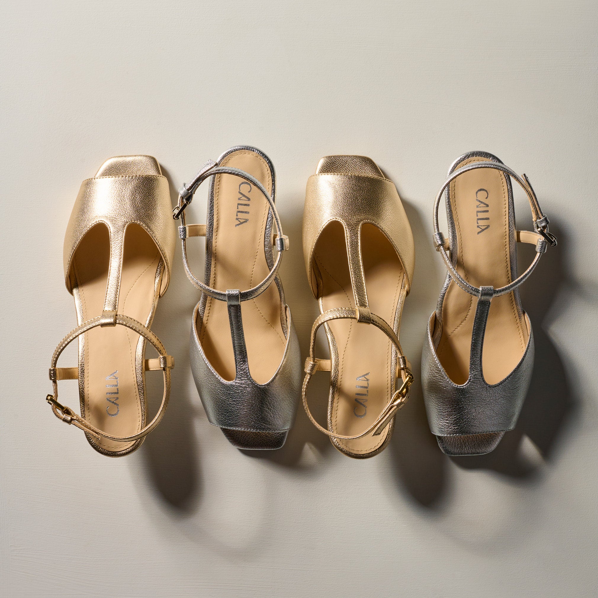 Pair of gold and silver open-toe shoes with 'Calla' branding on a neutral background