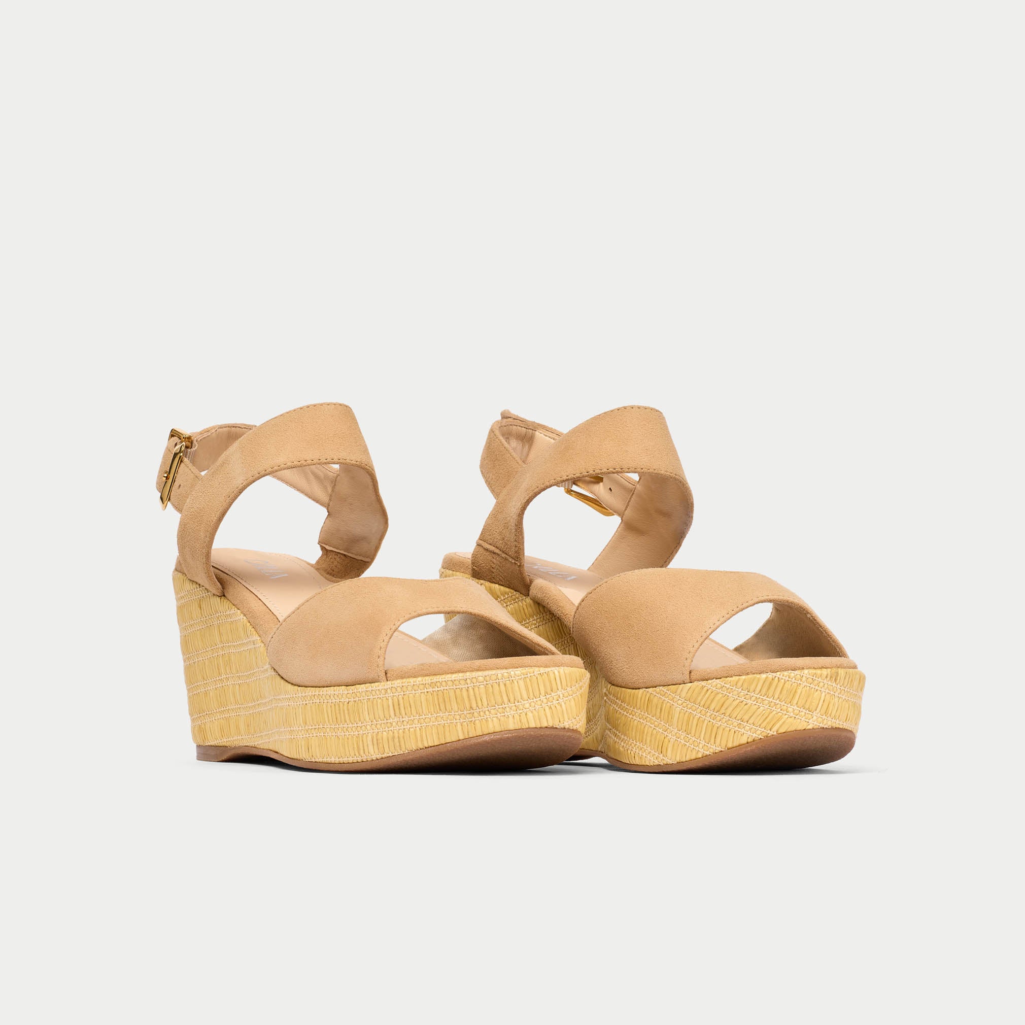 Pair of beige wedge sandals on a light gray background
