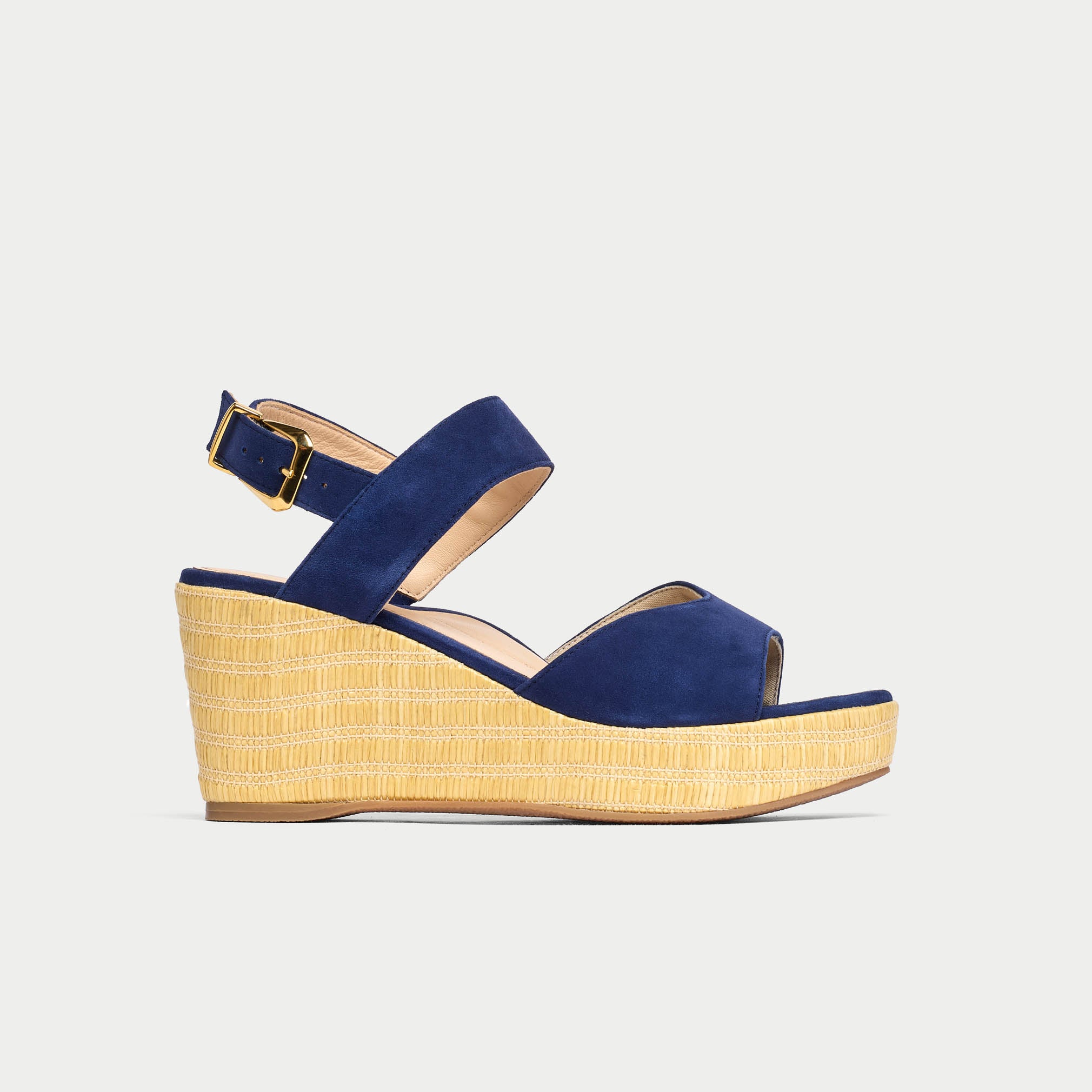 Navy wedge sandal with a straw sole on a light gray background