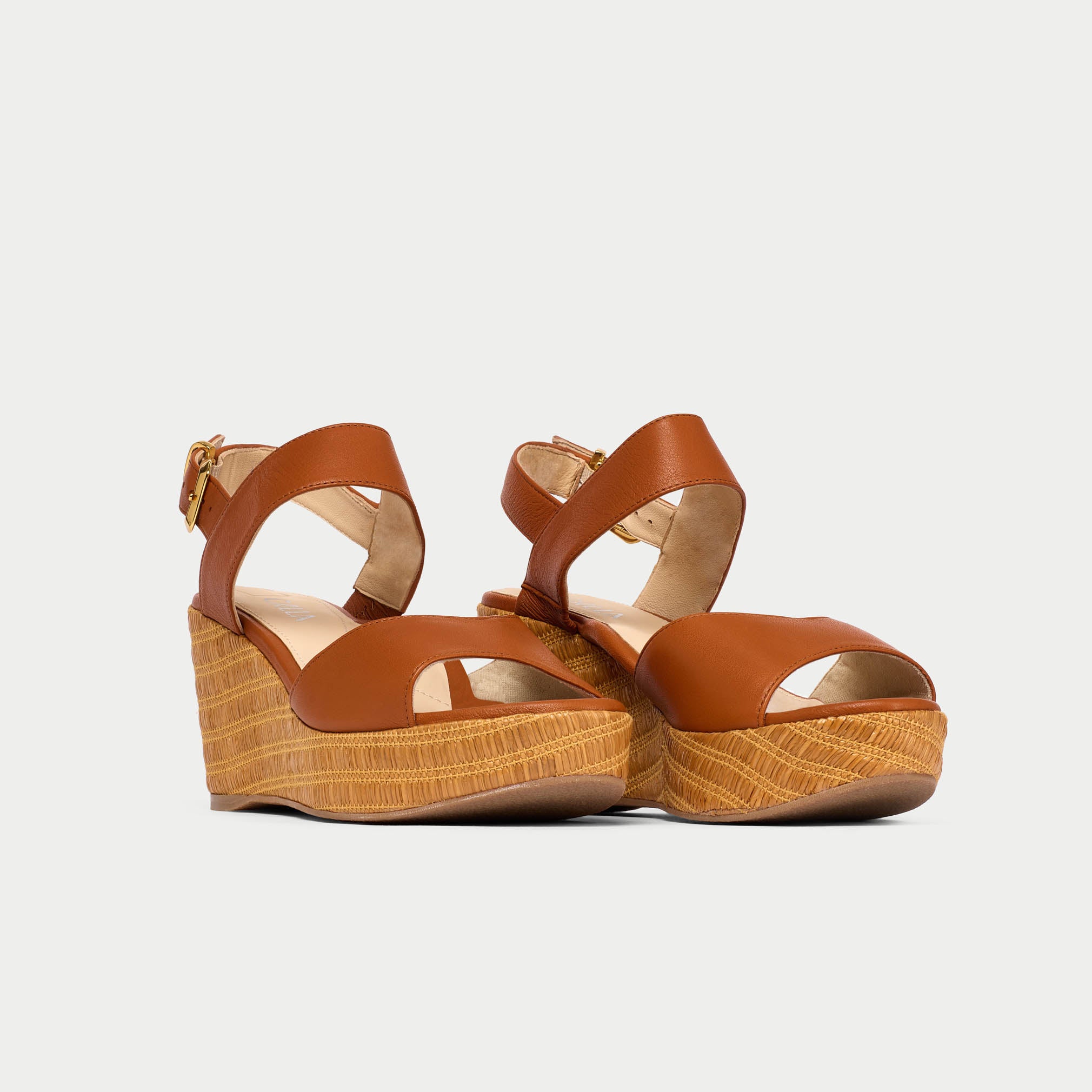 Brown wedge sandals with cork sole on a light gray background