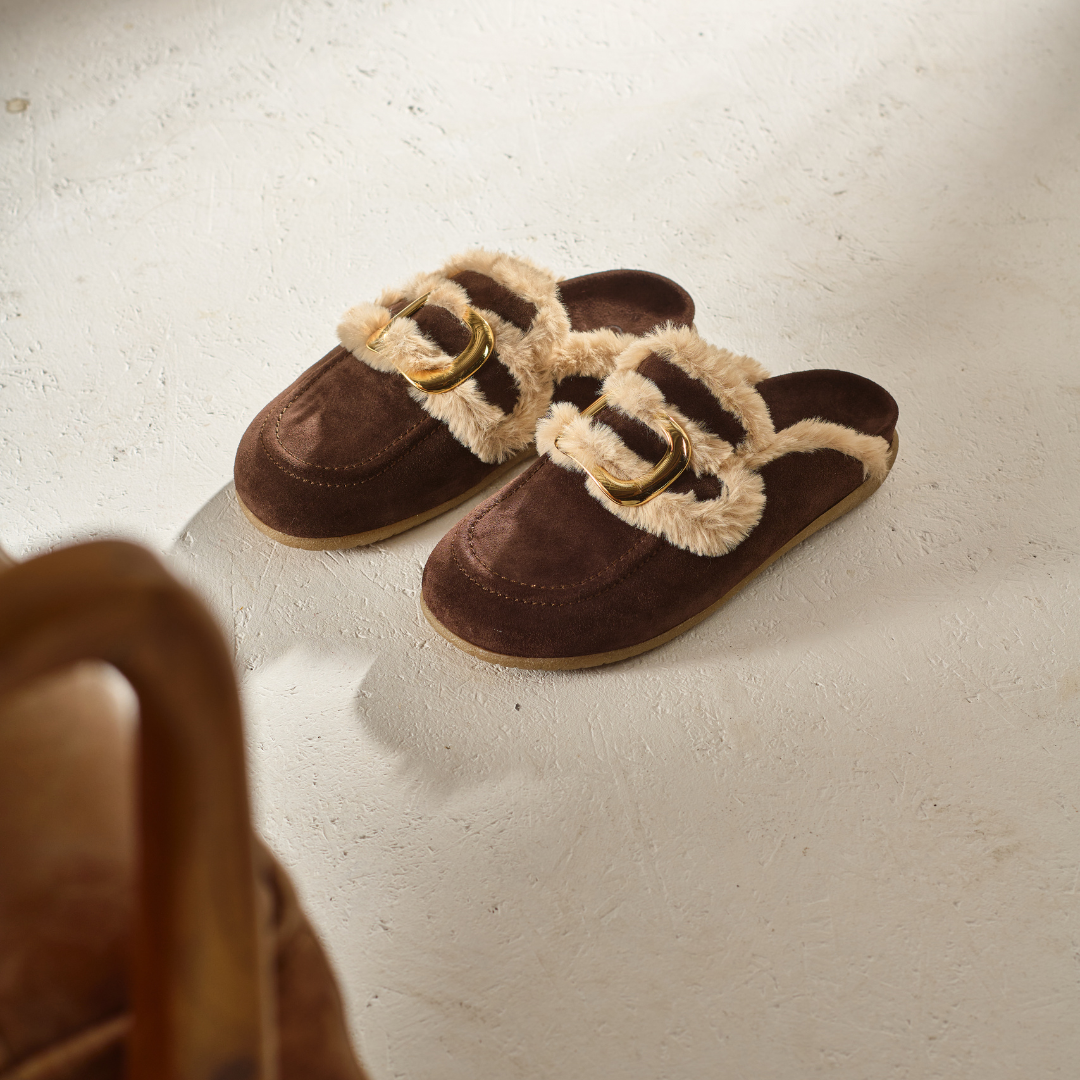 Brown slippers with fur trim on a light surface
