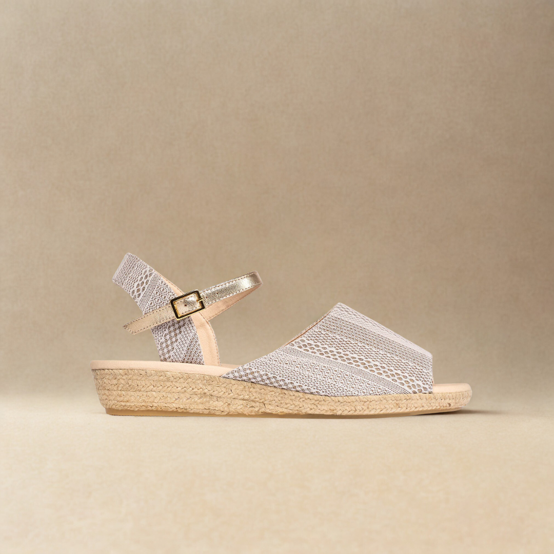 Silver sandal with a woven sole on a beige background