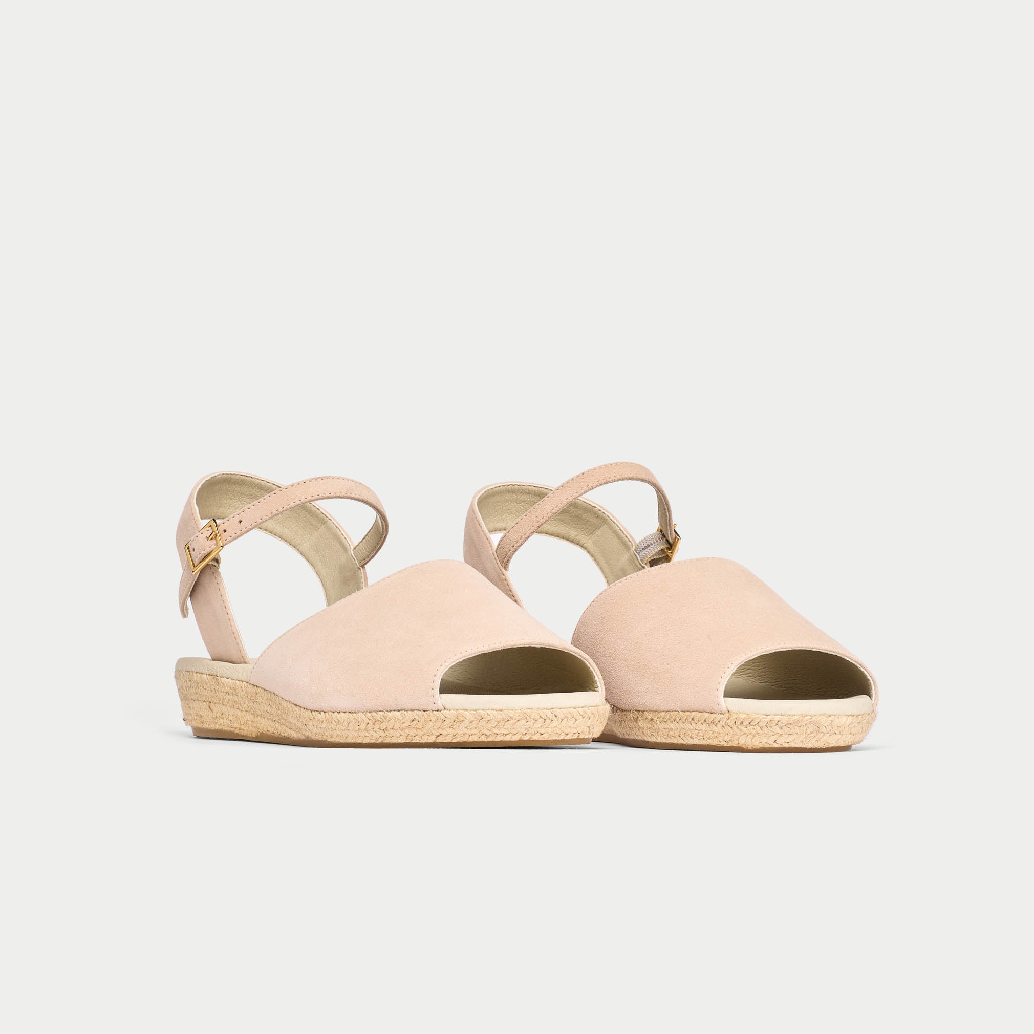 Pair of light pink sandals with espadrille soles on a white background
