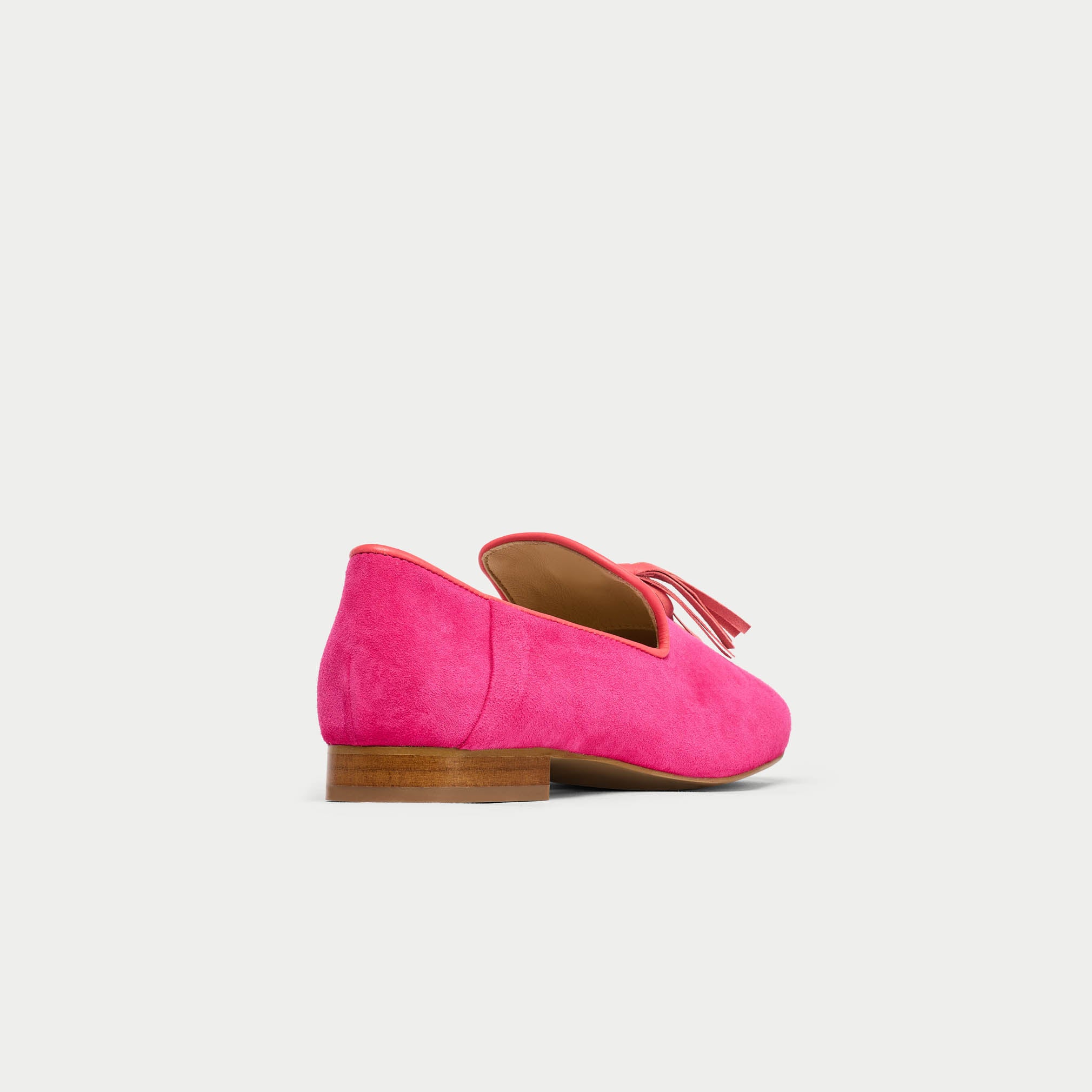 Pink suede shoe with a brown sole on a light gray background