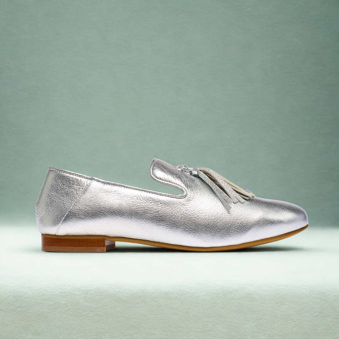 Silver loafer with tassels on teal background