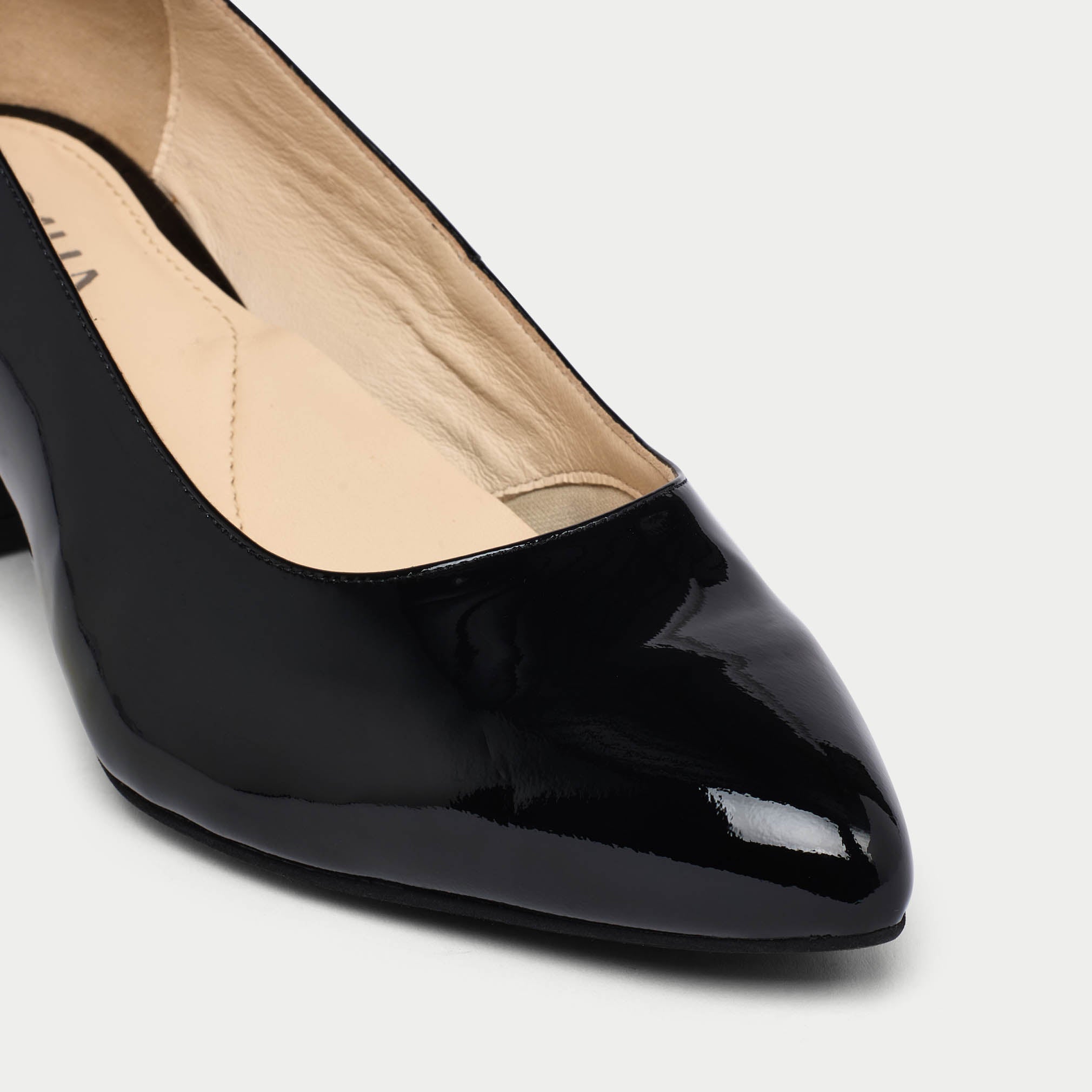 Black patent leather shoe on a light gray background