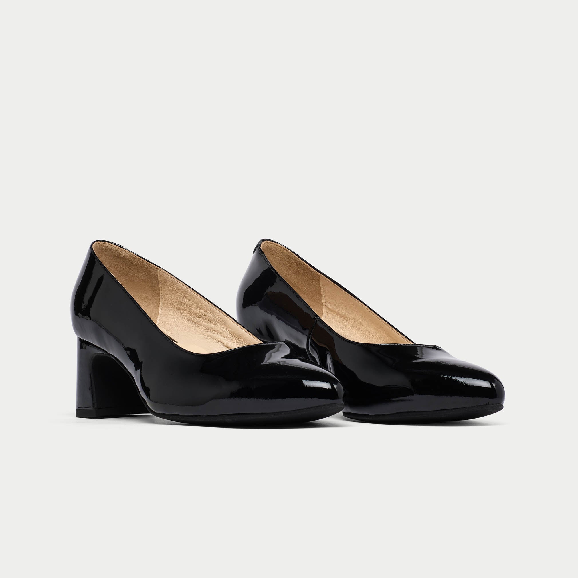 Pair of black patent leather high heels on a light gray background