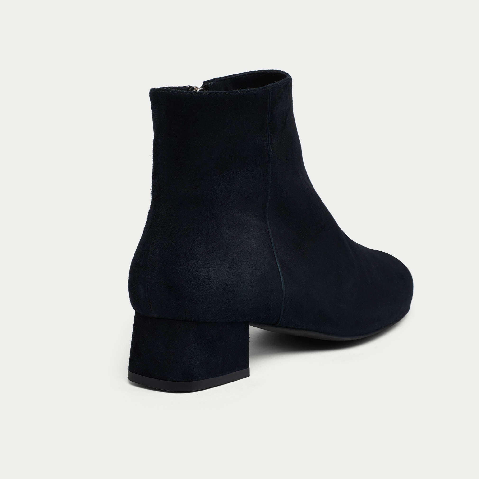 Black Lexie ankle boots on a light gray background heel close-up