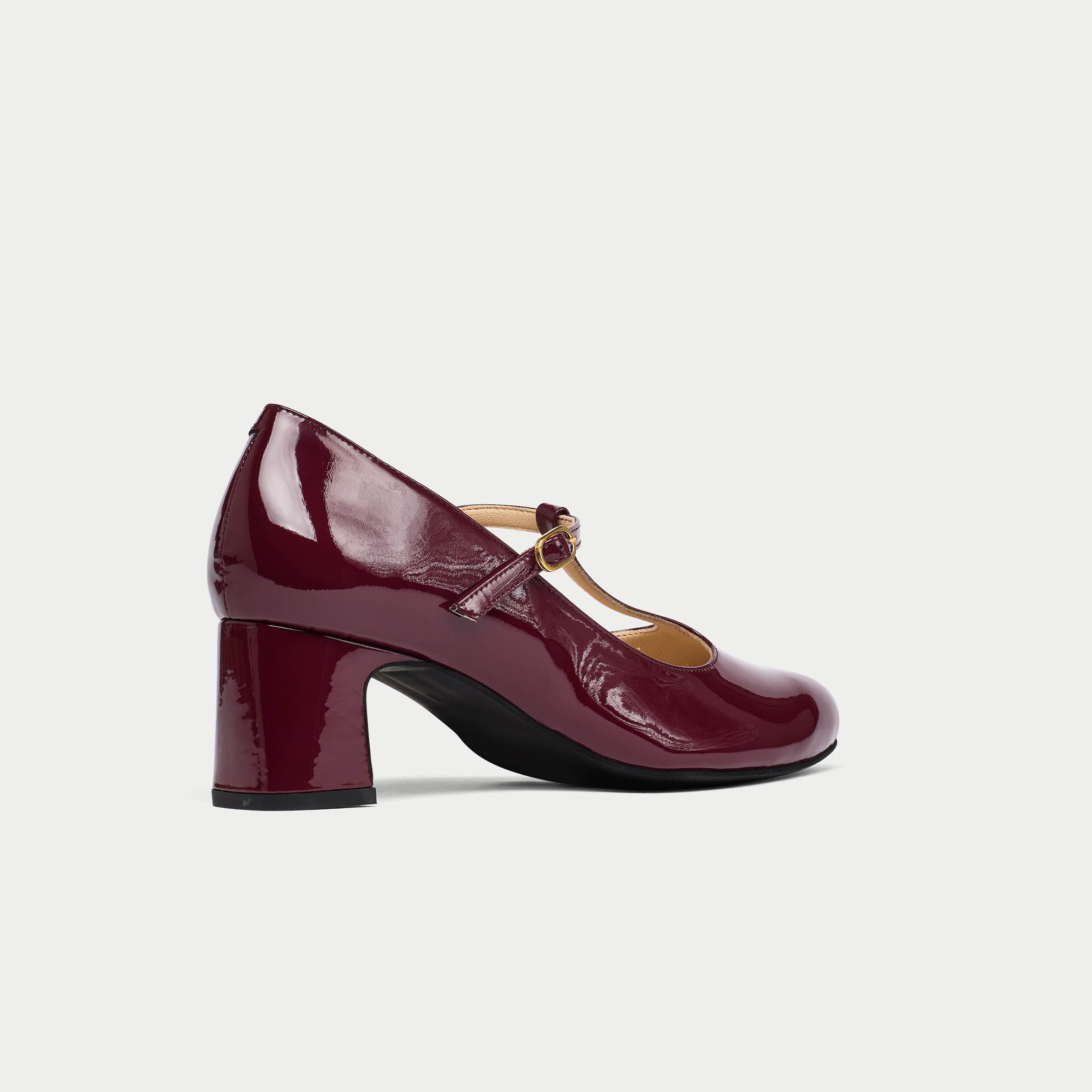 Maroon patent leather shoe with a block heel on a light gray background