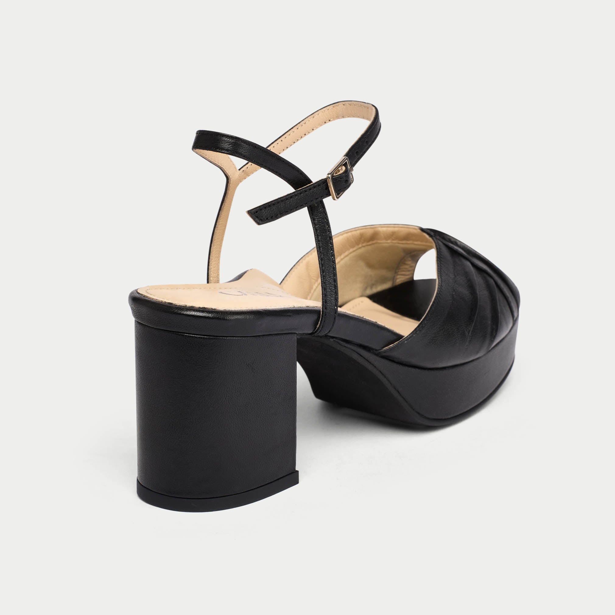 Black platform sandal with a thin strap on a light gray background