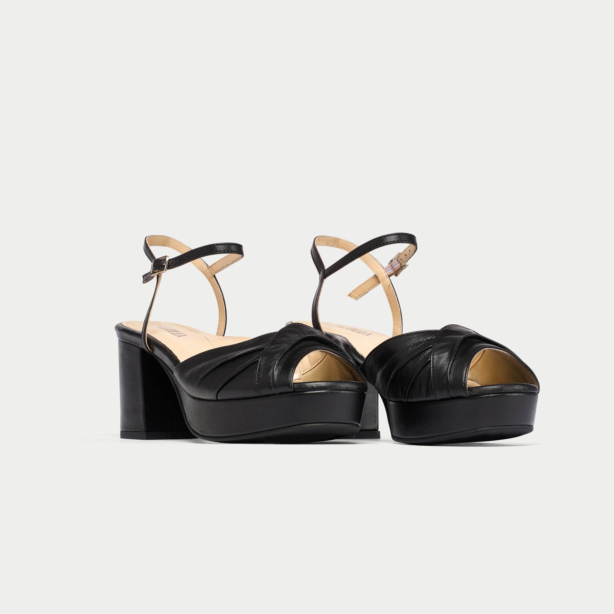Black platform sandals with thin straps on a light gray background