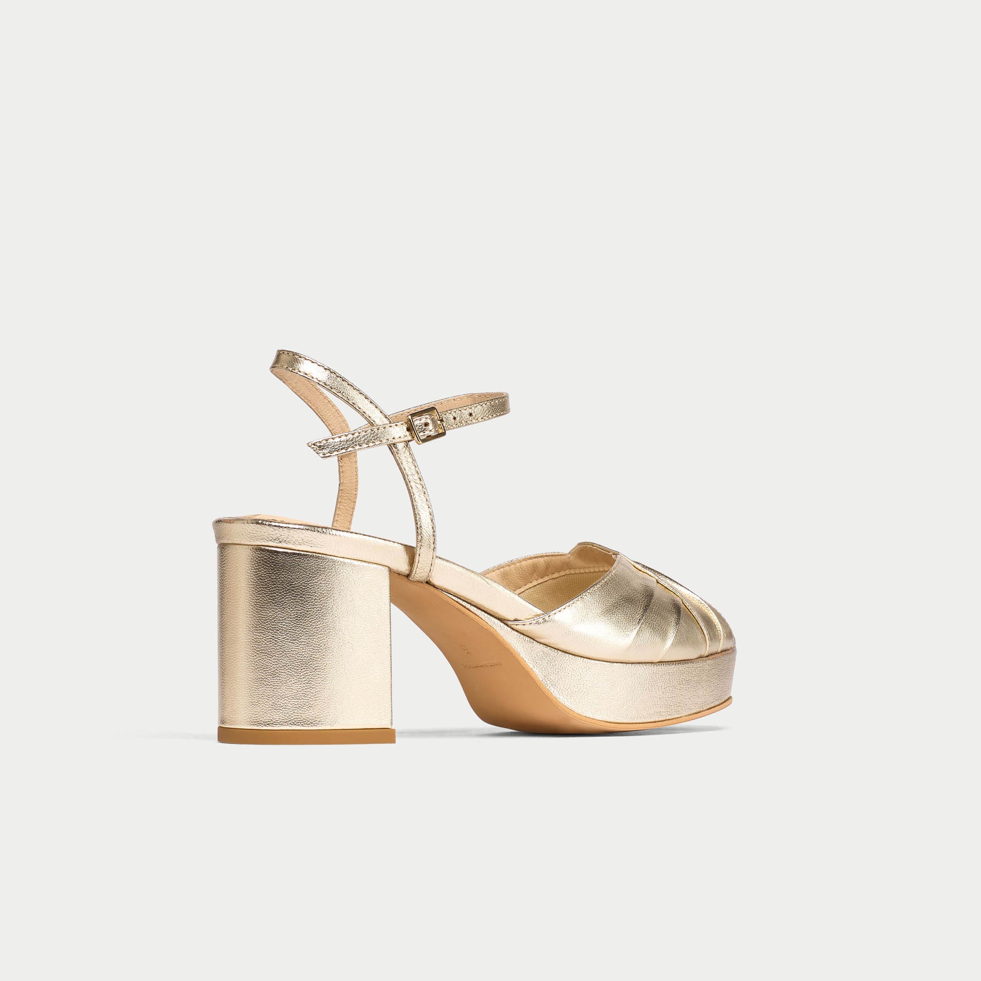 Gold high-heeled shoe on a light gray background