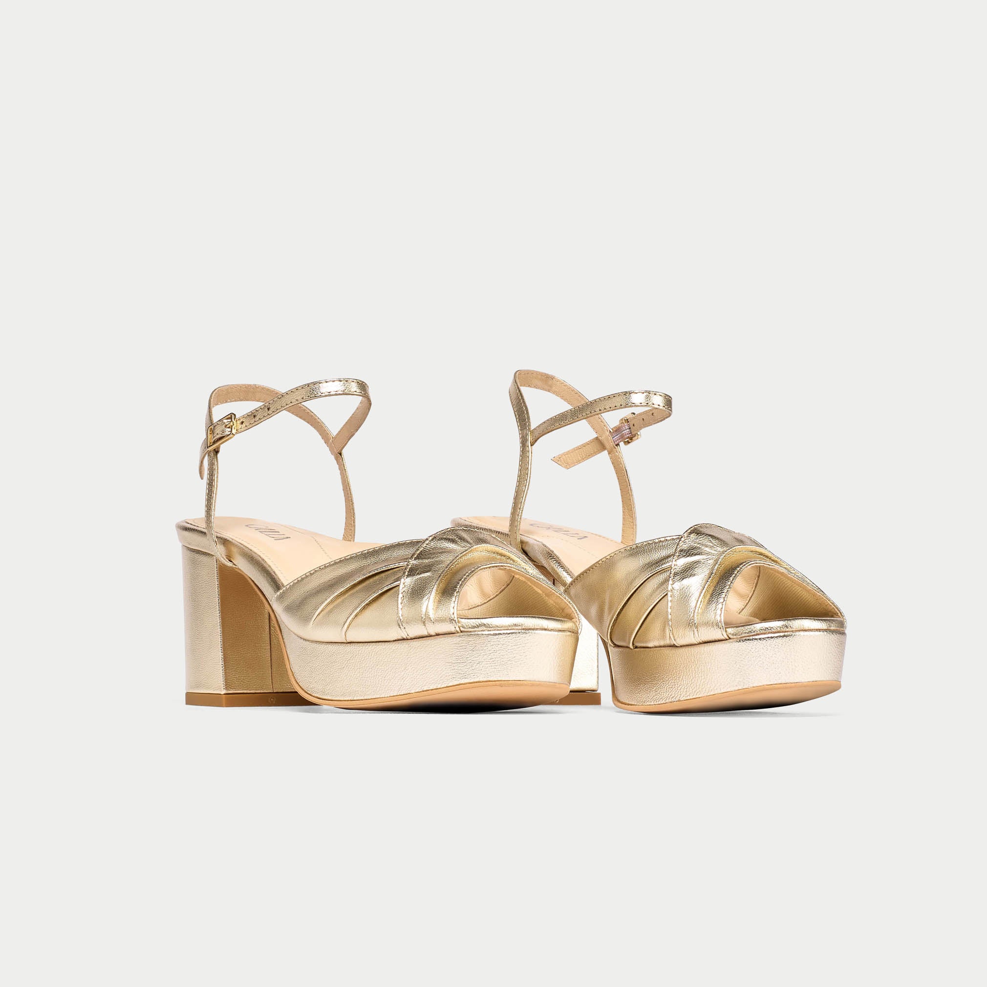 Gold high-heeled sandals on a light gray background