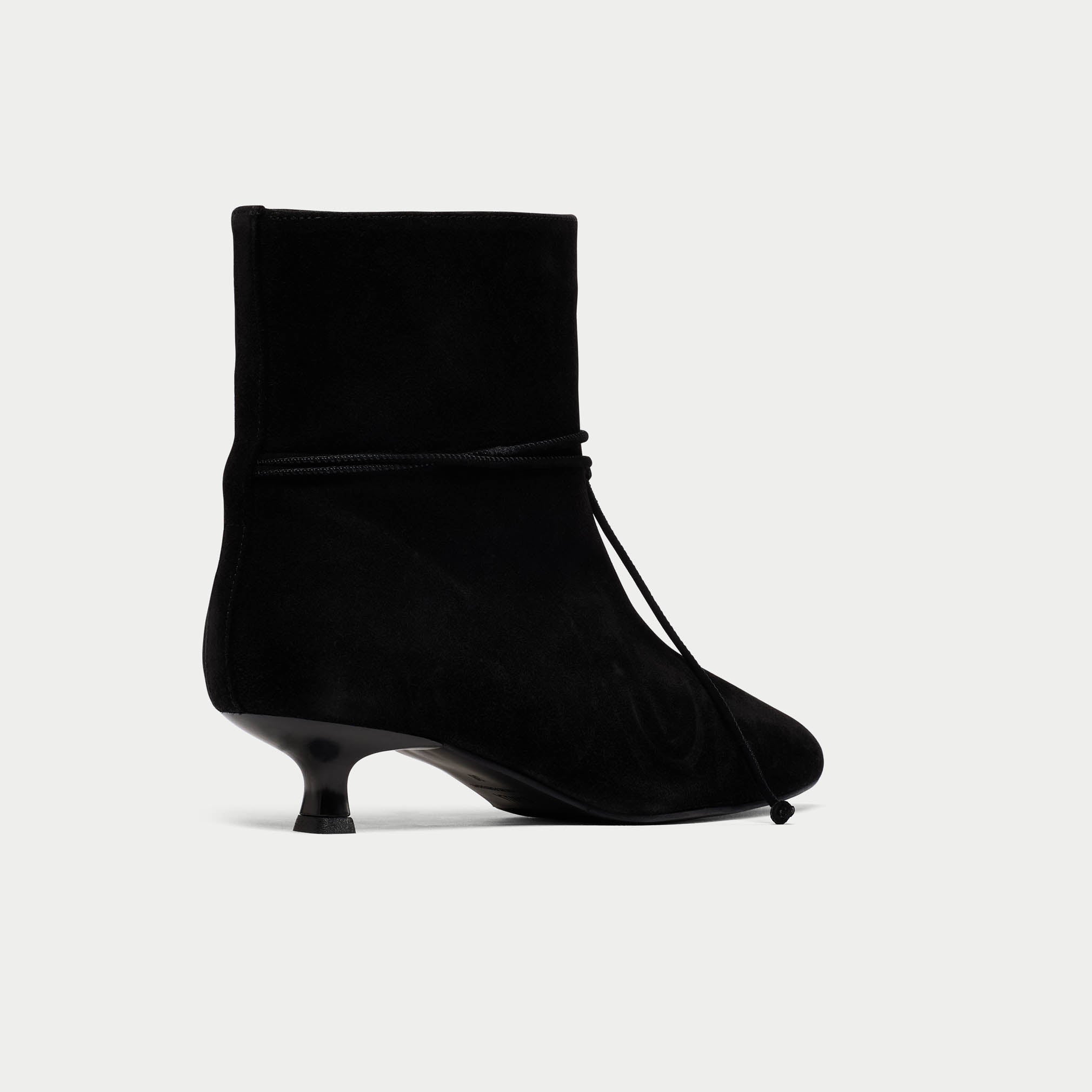 Black ankle boot with a kitten heel on a light gray background