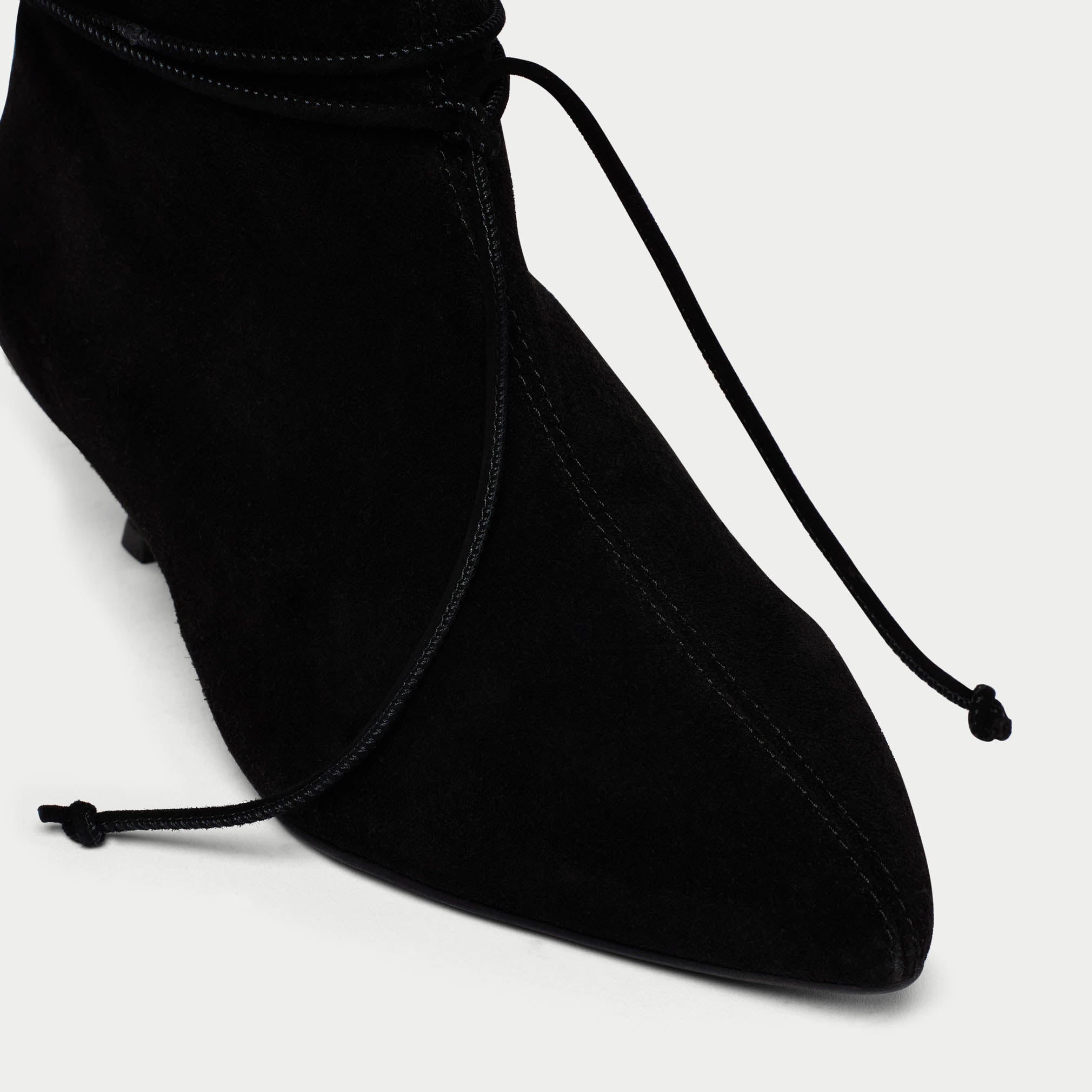 Black ankle boot with drawstring on a light gray background