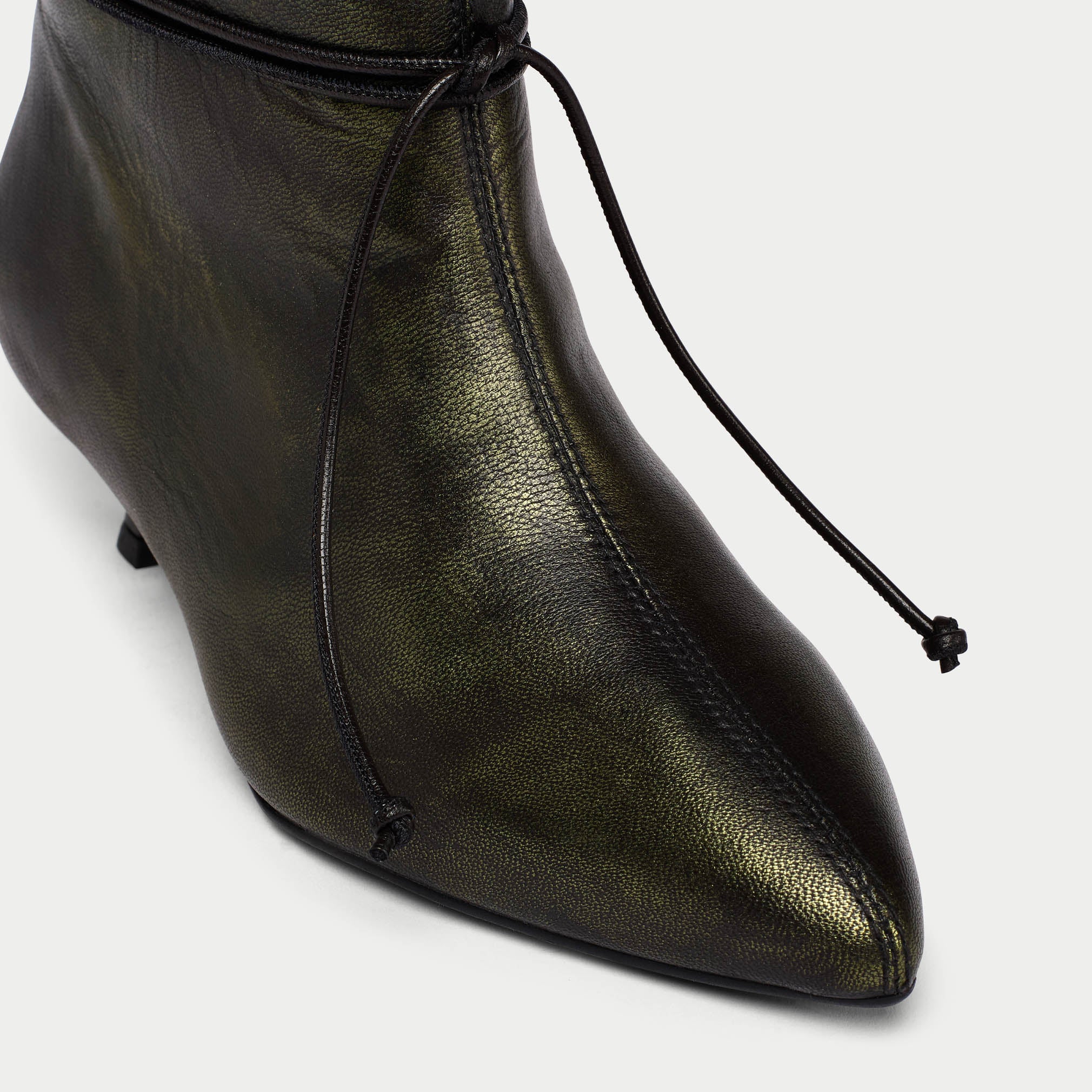 Black leather ankle boot with a pointed toe on a light gray background