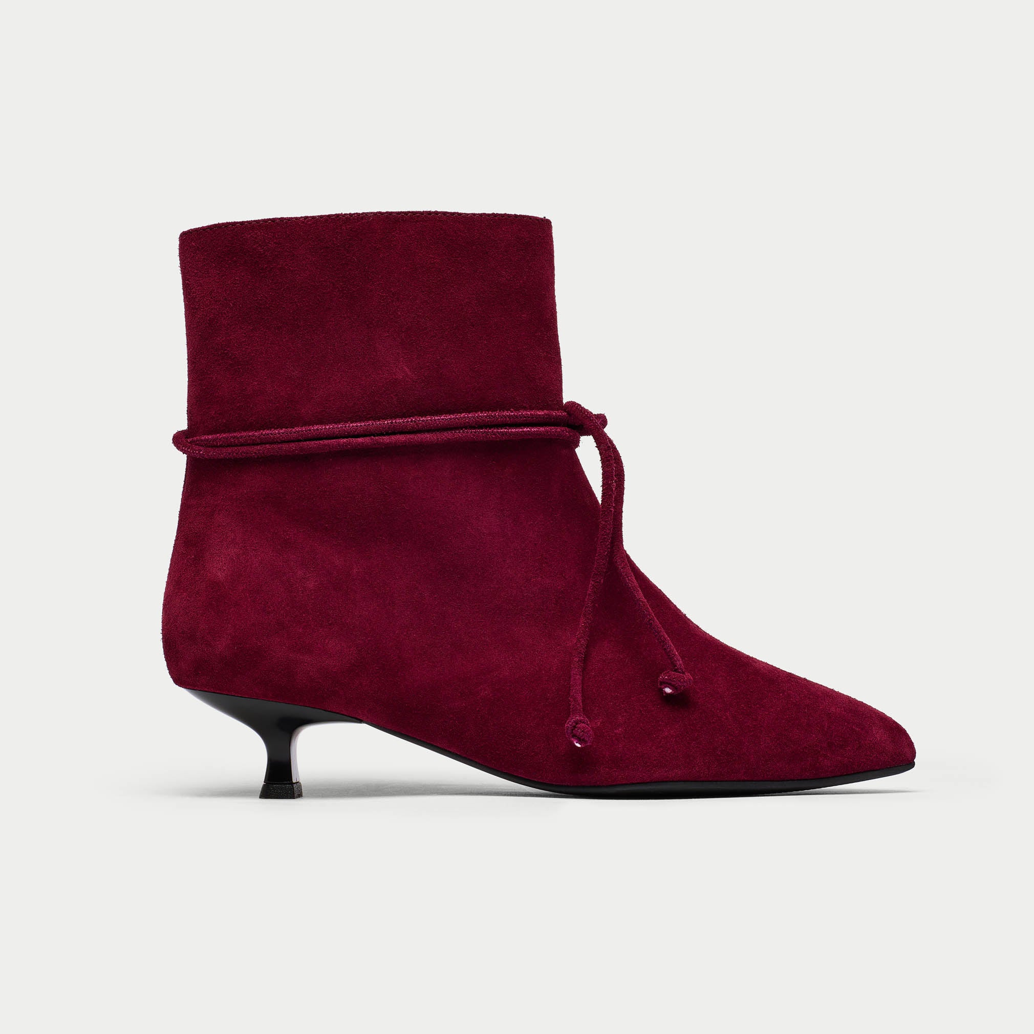 Maroon ankle boot with a pointed toe and kitten heel on a light gray background