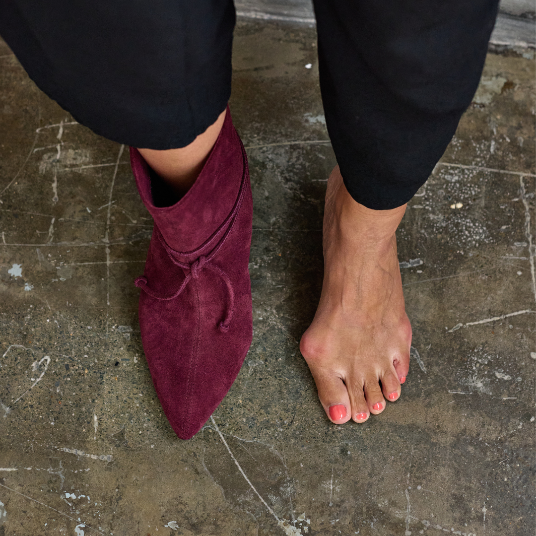 Mauve suede ankle boots worn on a textured floor.