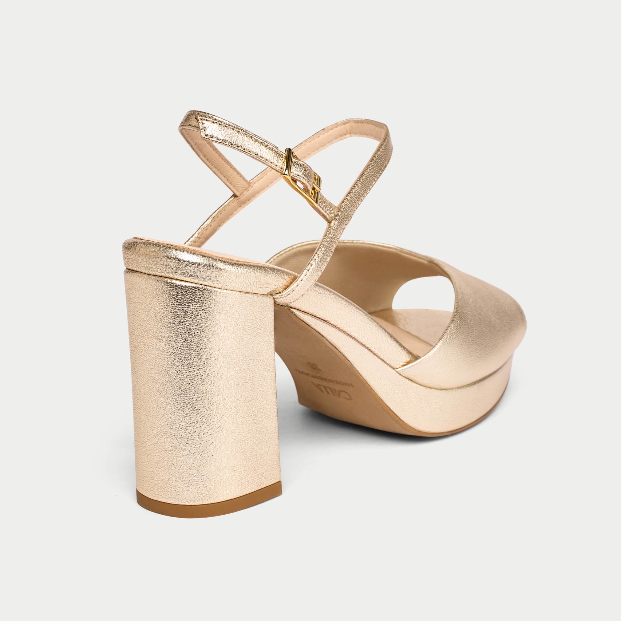 Gold high-heeled shoe on a light gray background