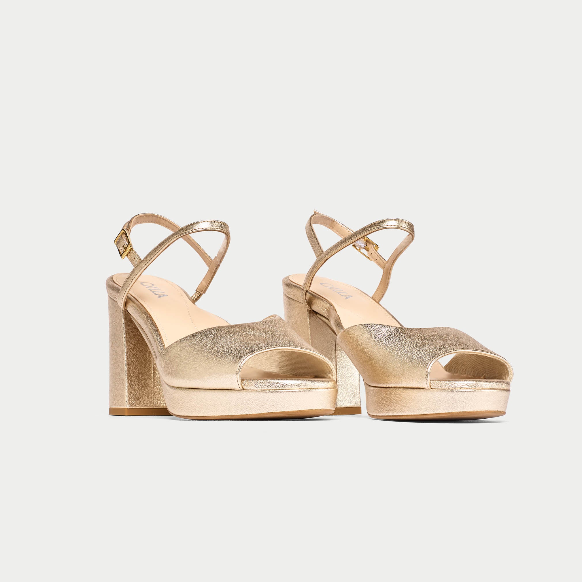 Pair of gold high-heeled sandals on a light gray background