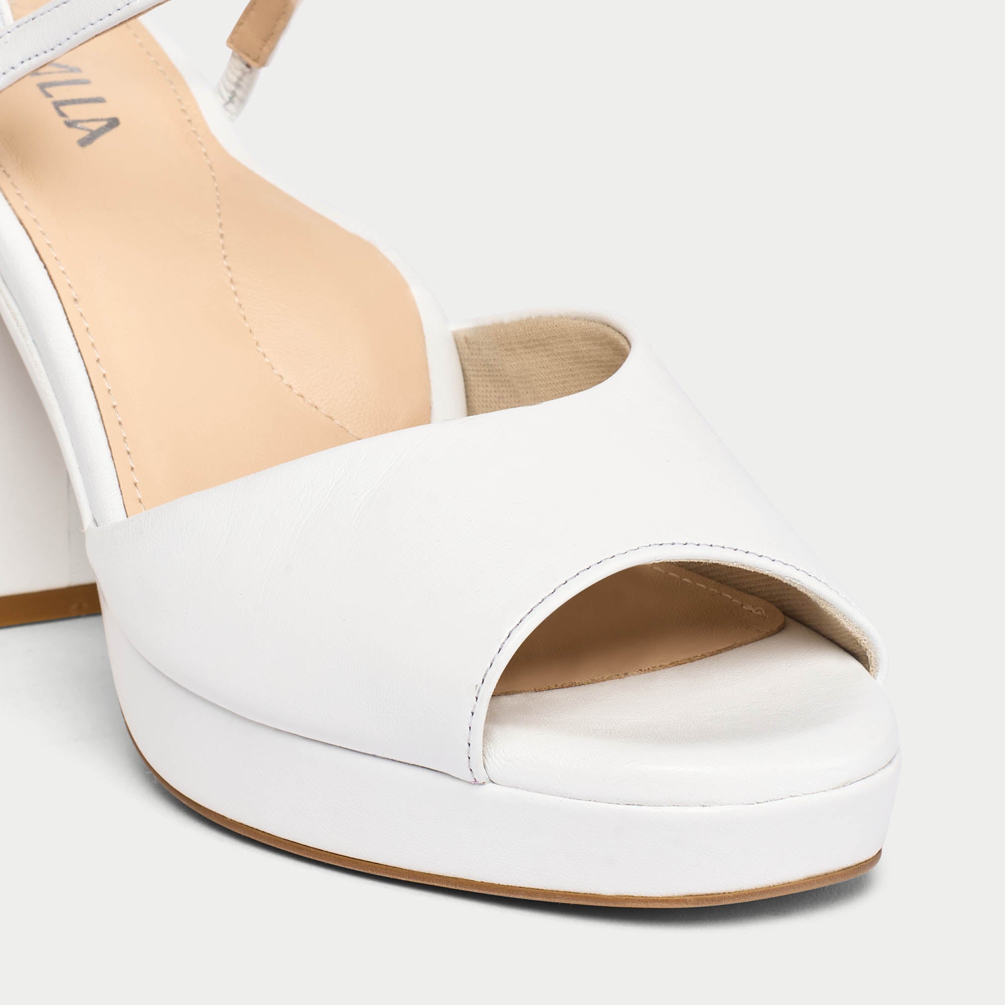 White sandal with beige interior on a light gray background