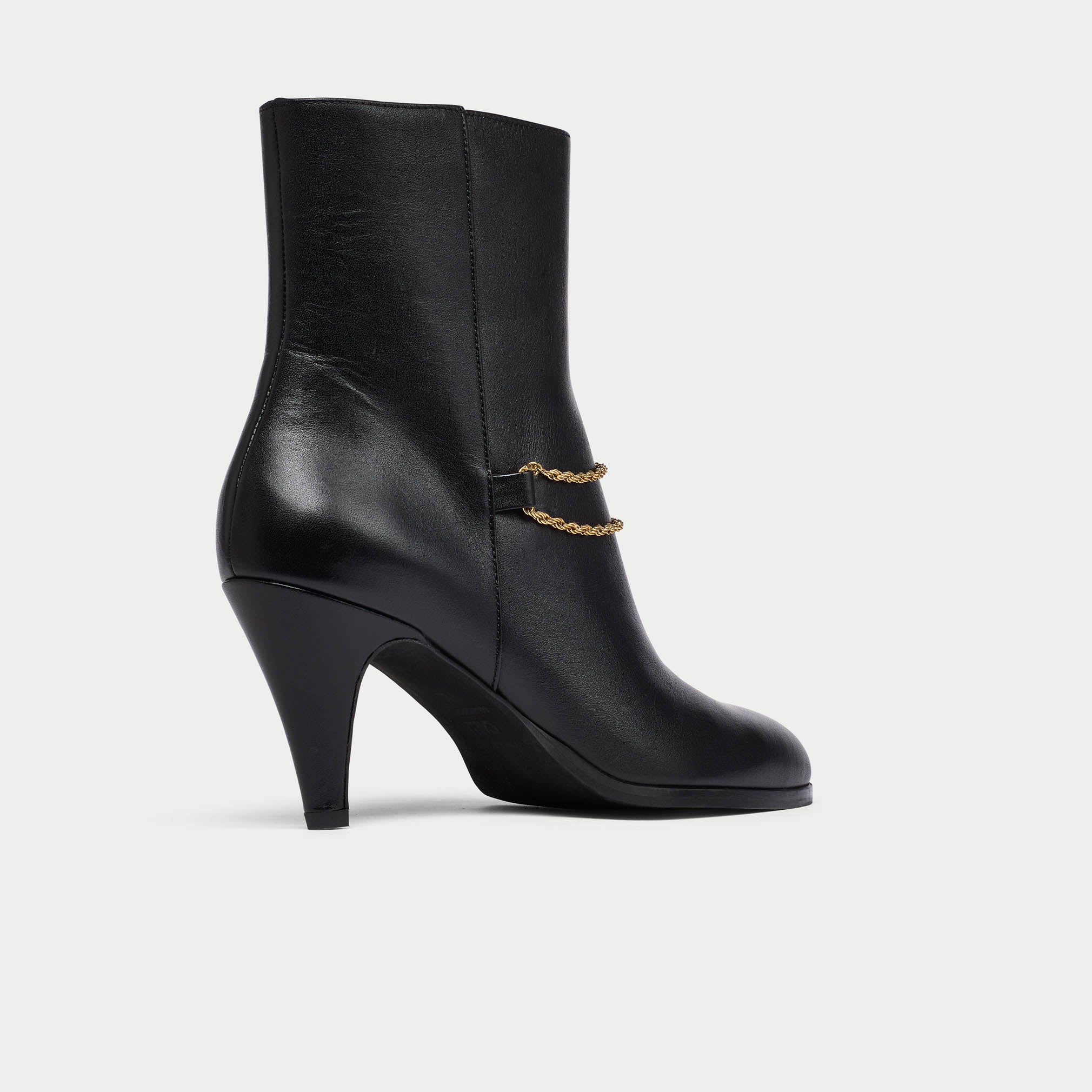 Black Maya ankle boot with a gold chain on a light gray background