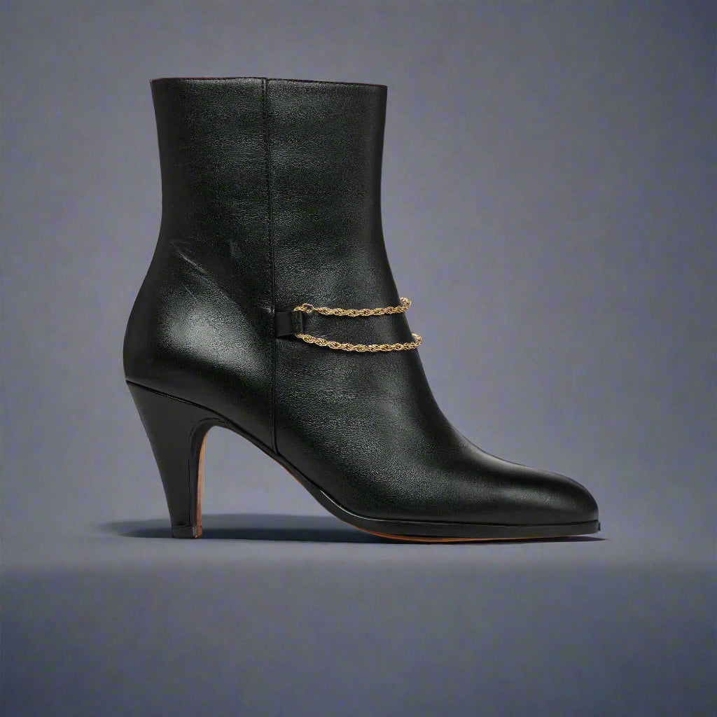Maya Black ankle boot for bunions with a gold chain on a navy background