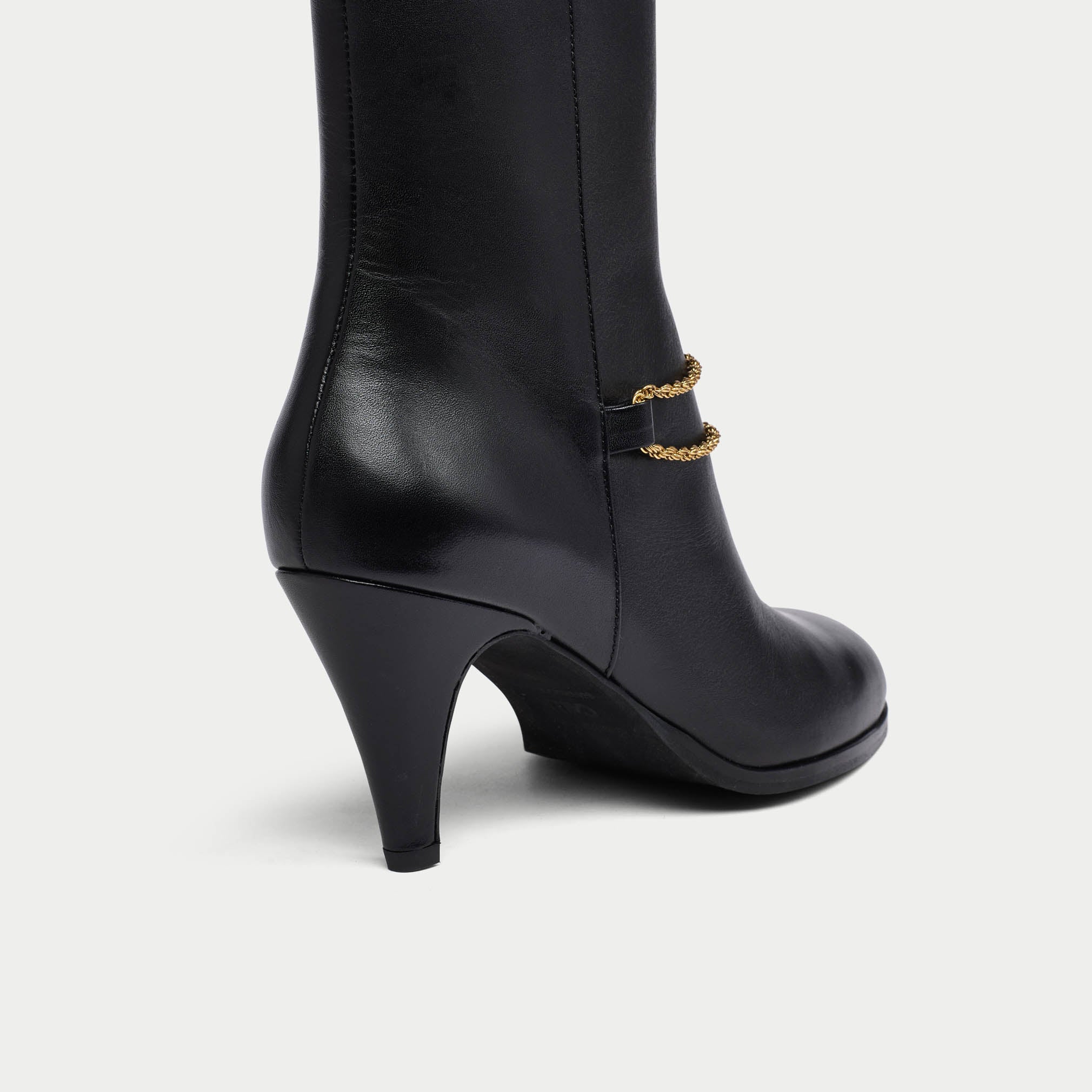 BlackMaya boot with gold chain detail on a white background heel close-up