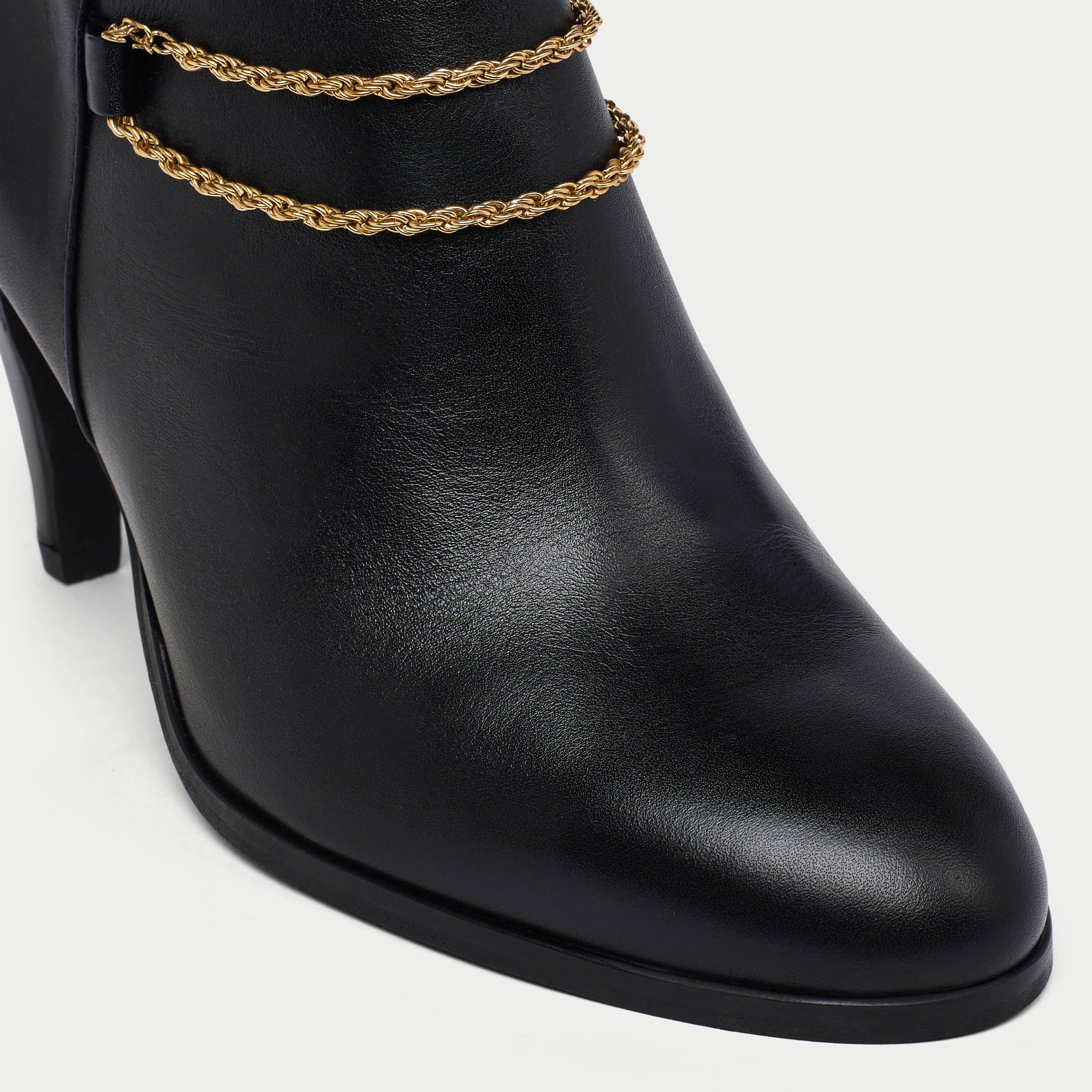 Maya Black ankle boot with gold chain detail on a white background tip close-up
