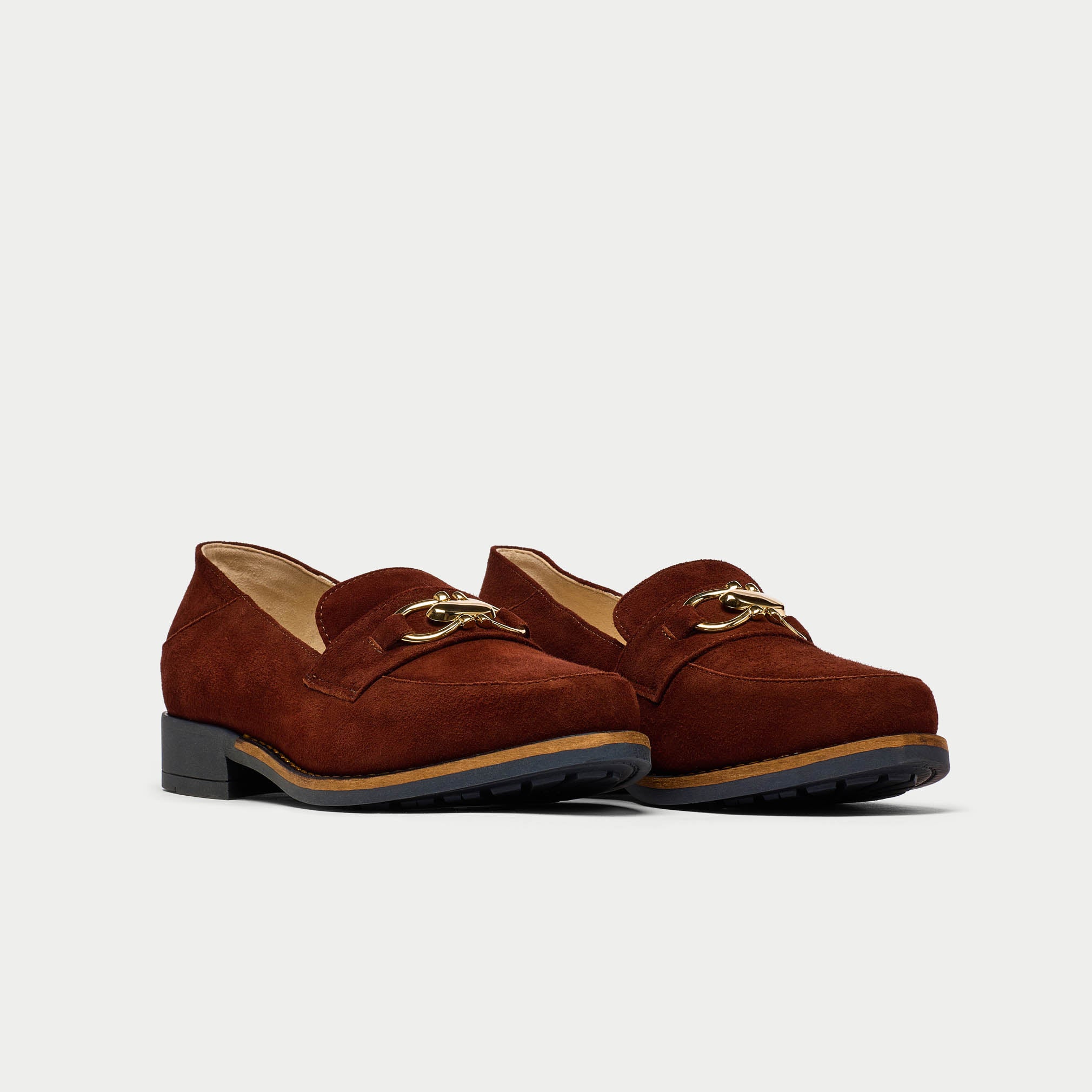 Pair of brown loafers with gold accents on a light gray background