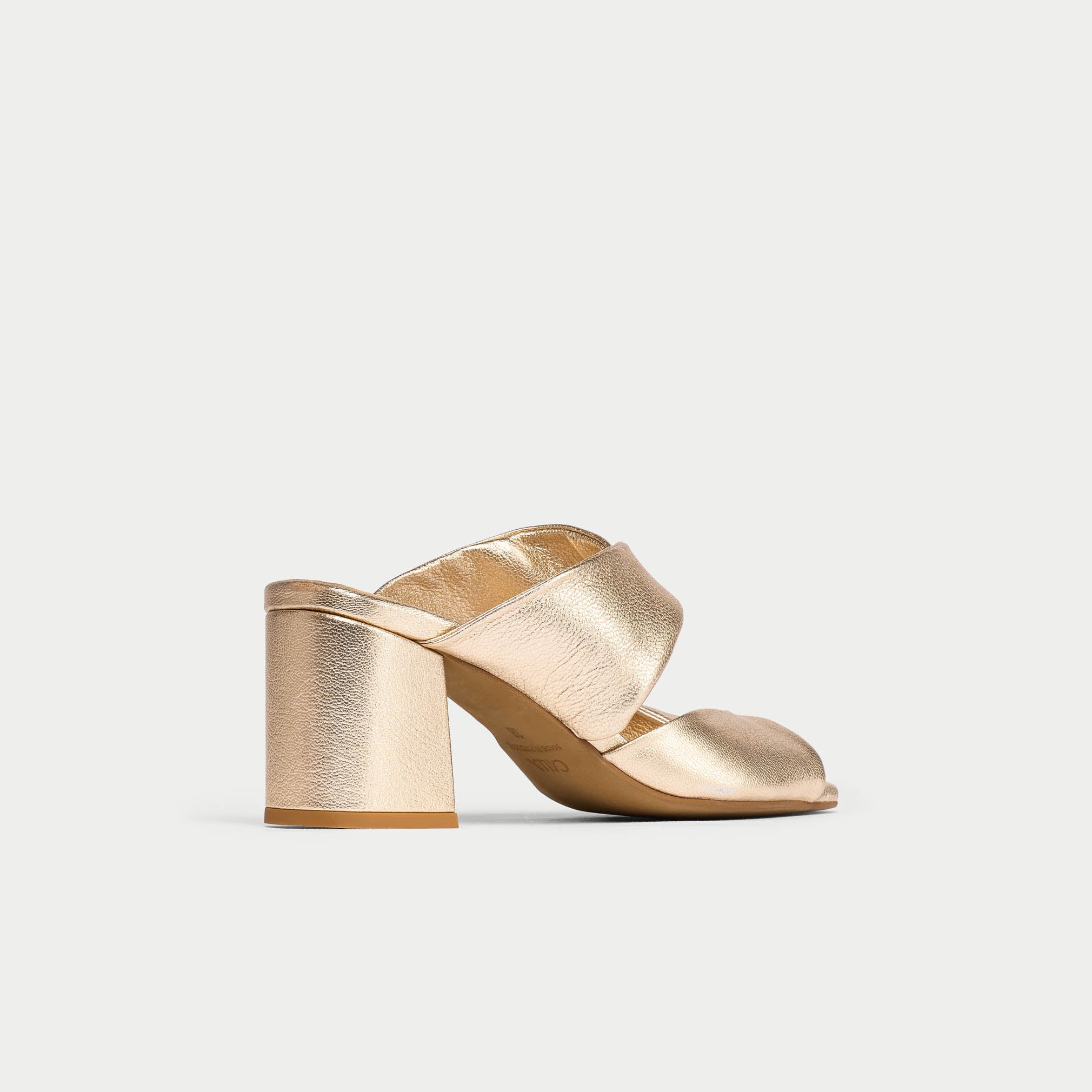 Gold high-heeled shoe on a light gray background