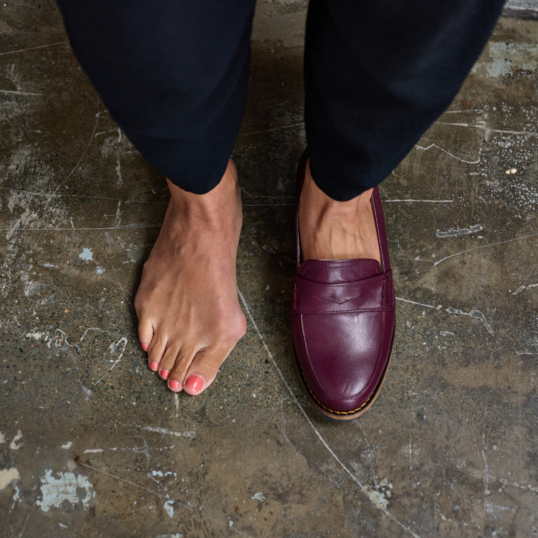 Person wearing a cherry Nadia loafer on a concrete floor