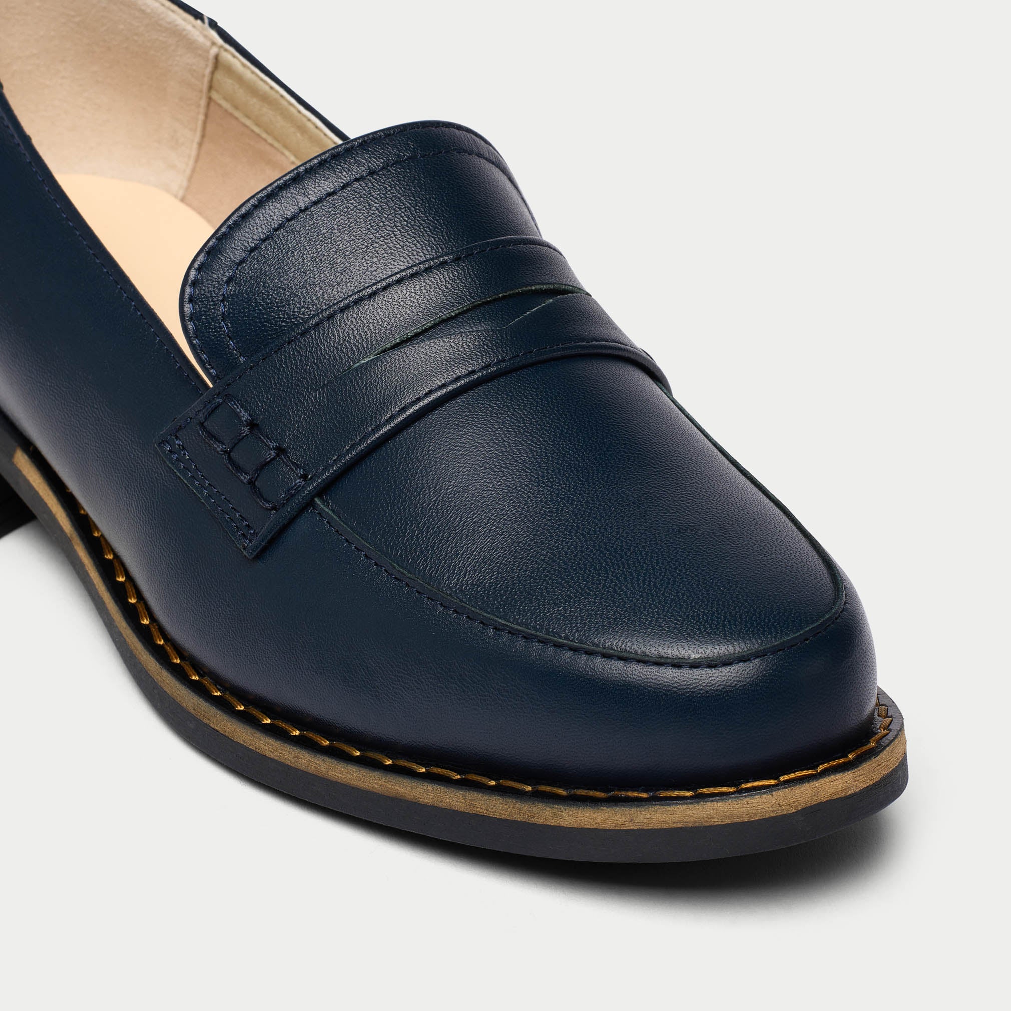 Navy blue loafer shoe on a light gray background