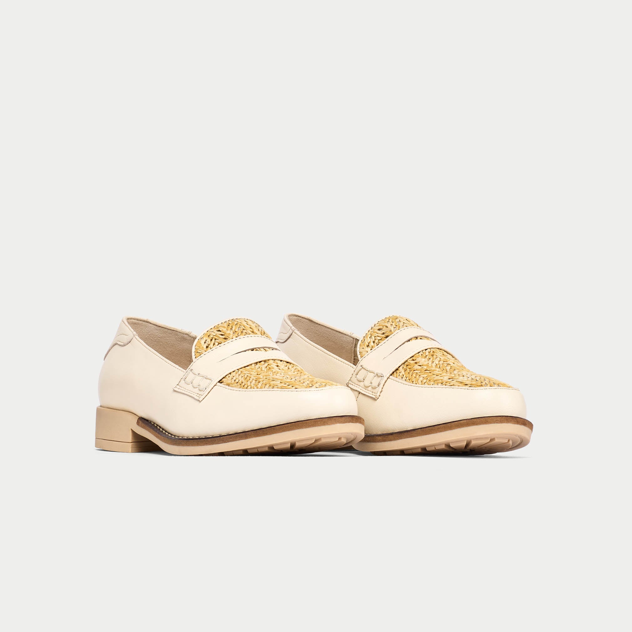 Pair of cream loafers with gold accents on a light gray background