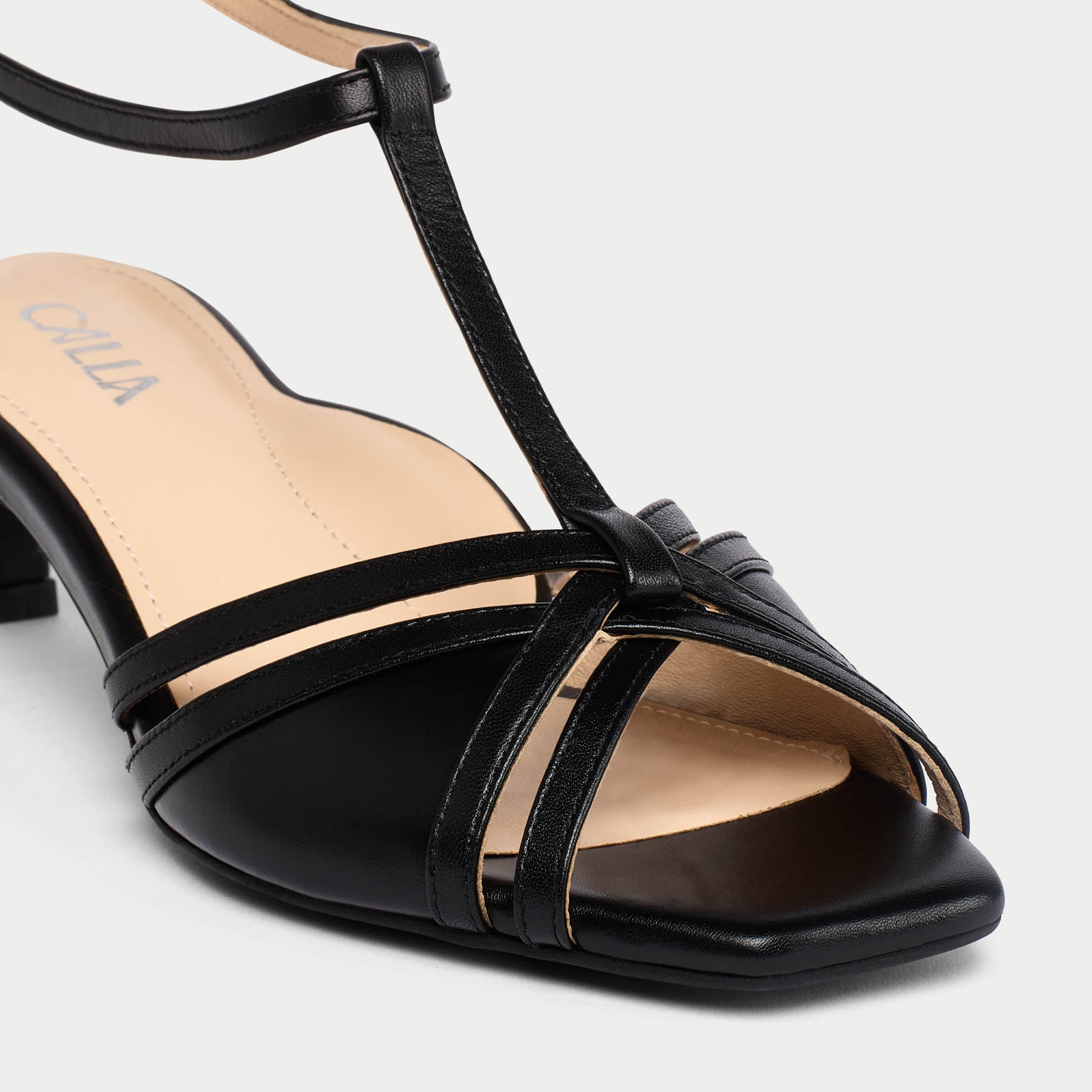 Black sandal with multiple straps on a light gray background
