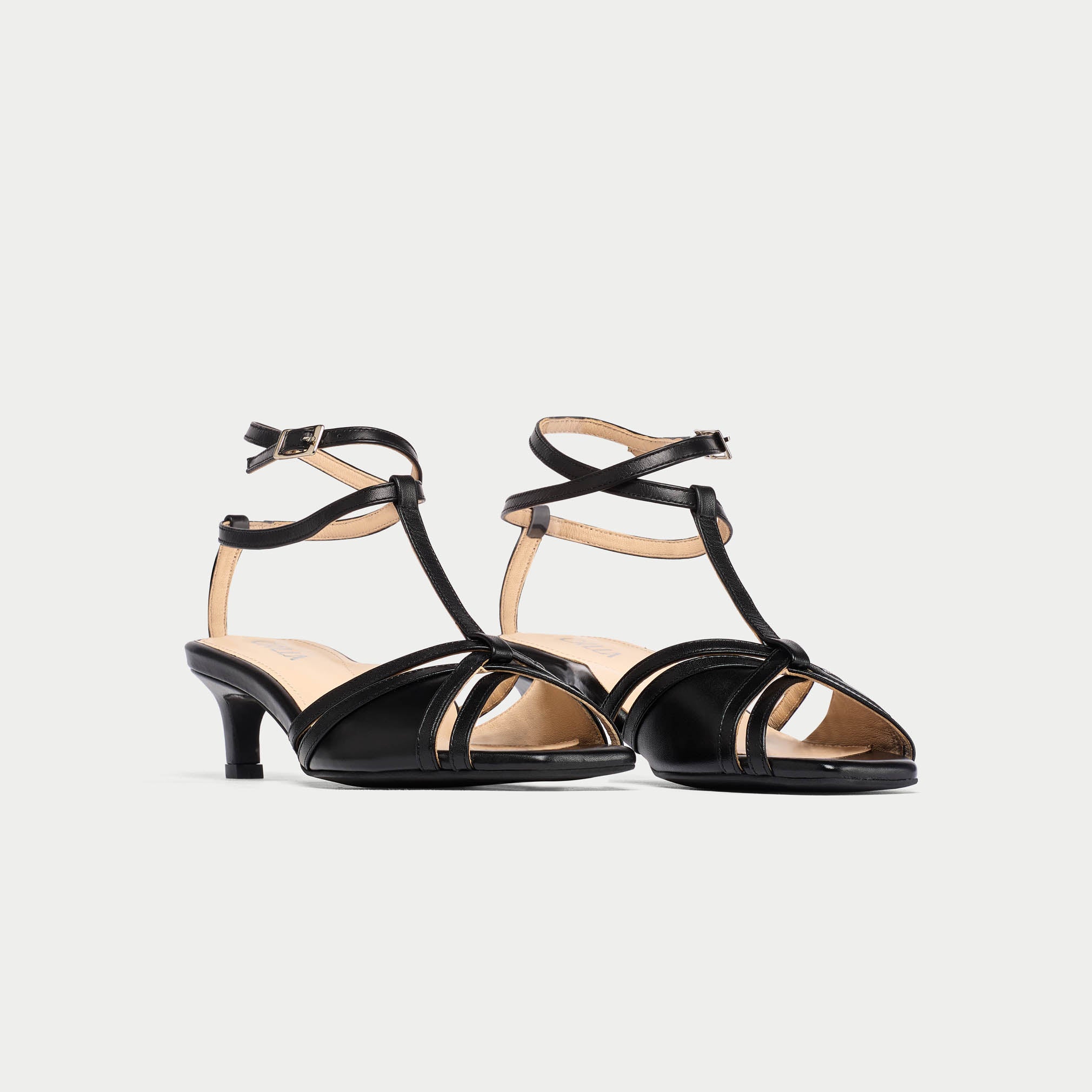 Pair of black kitten-heeled sandals on a light gray background