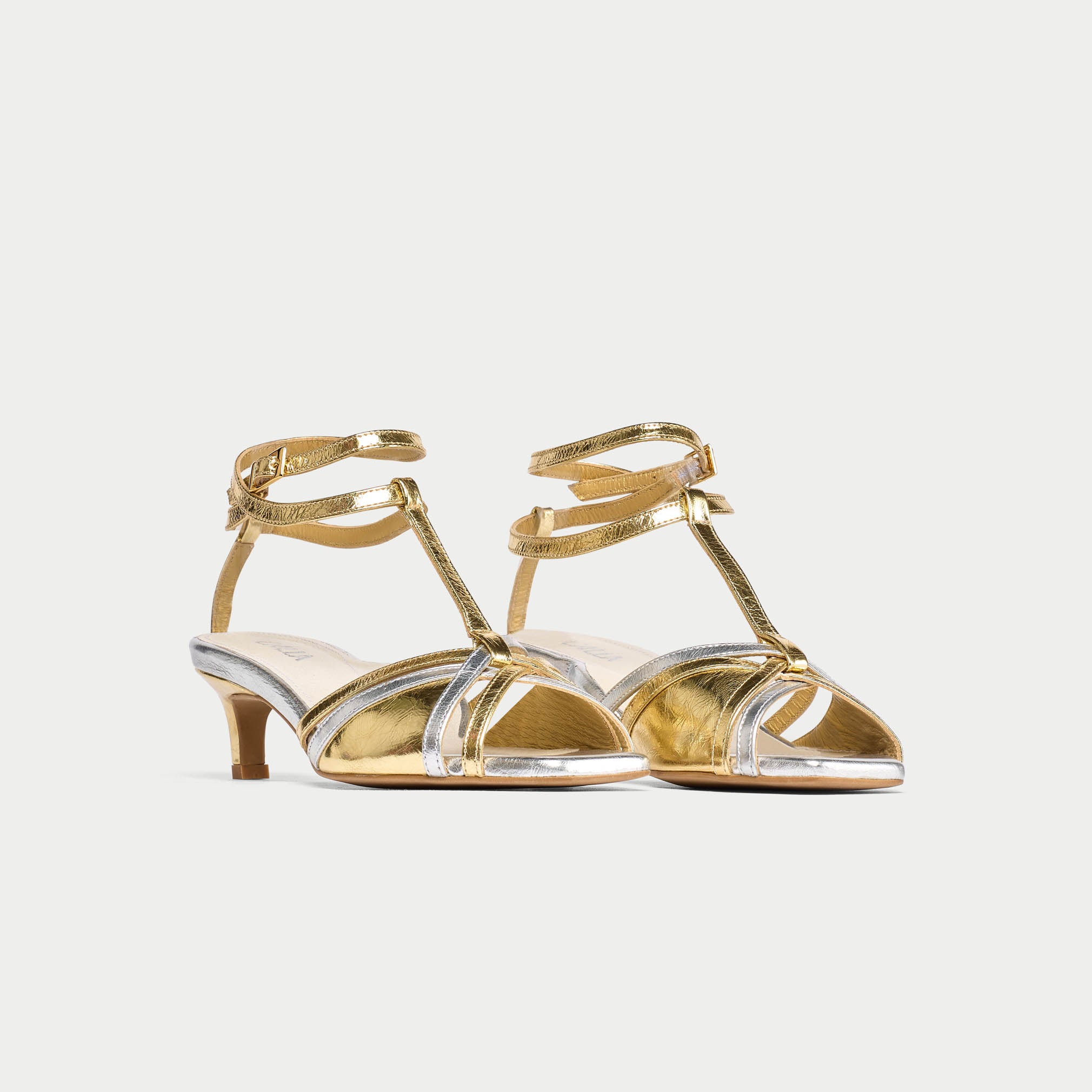 Gold kitten-heeled shoes with clear straps on a white background