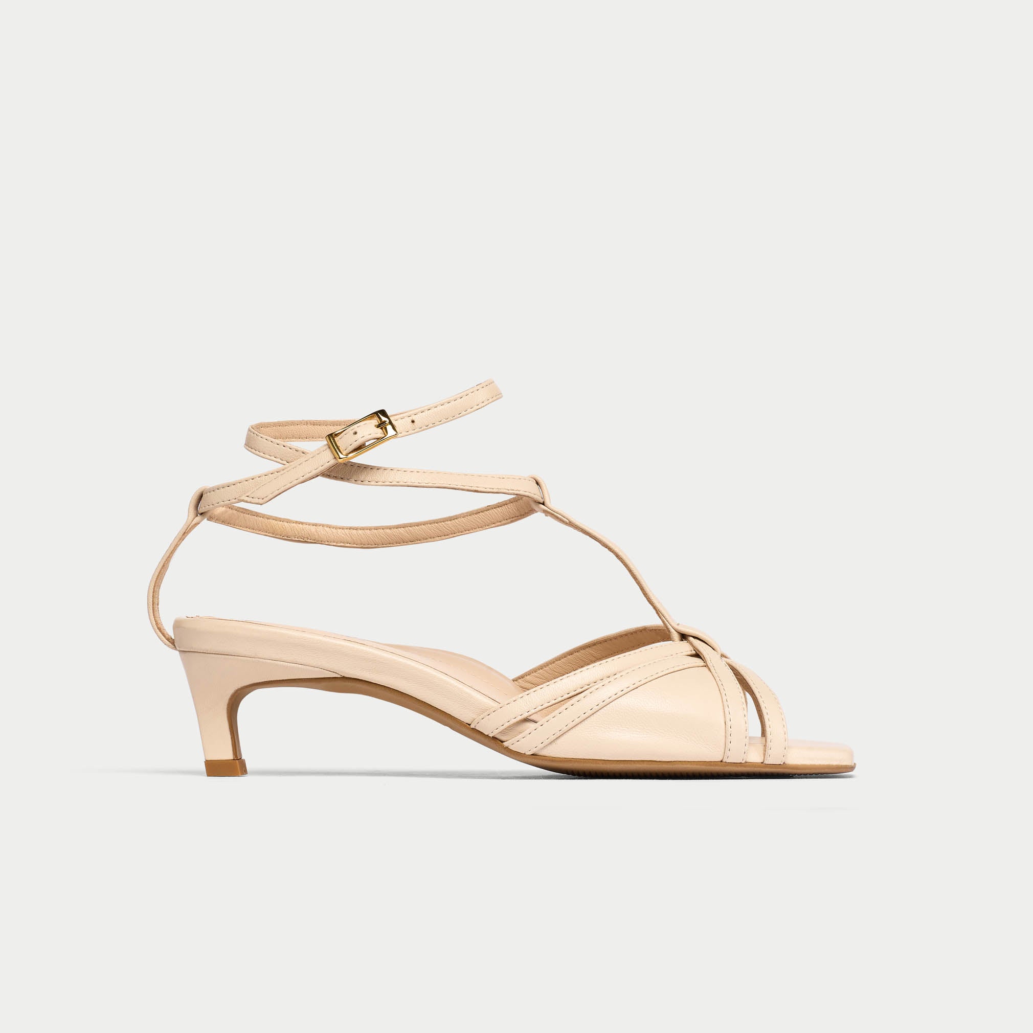 Beige sandal with thin straps on a light beige background