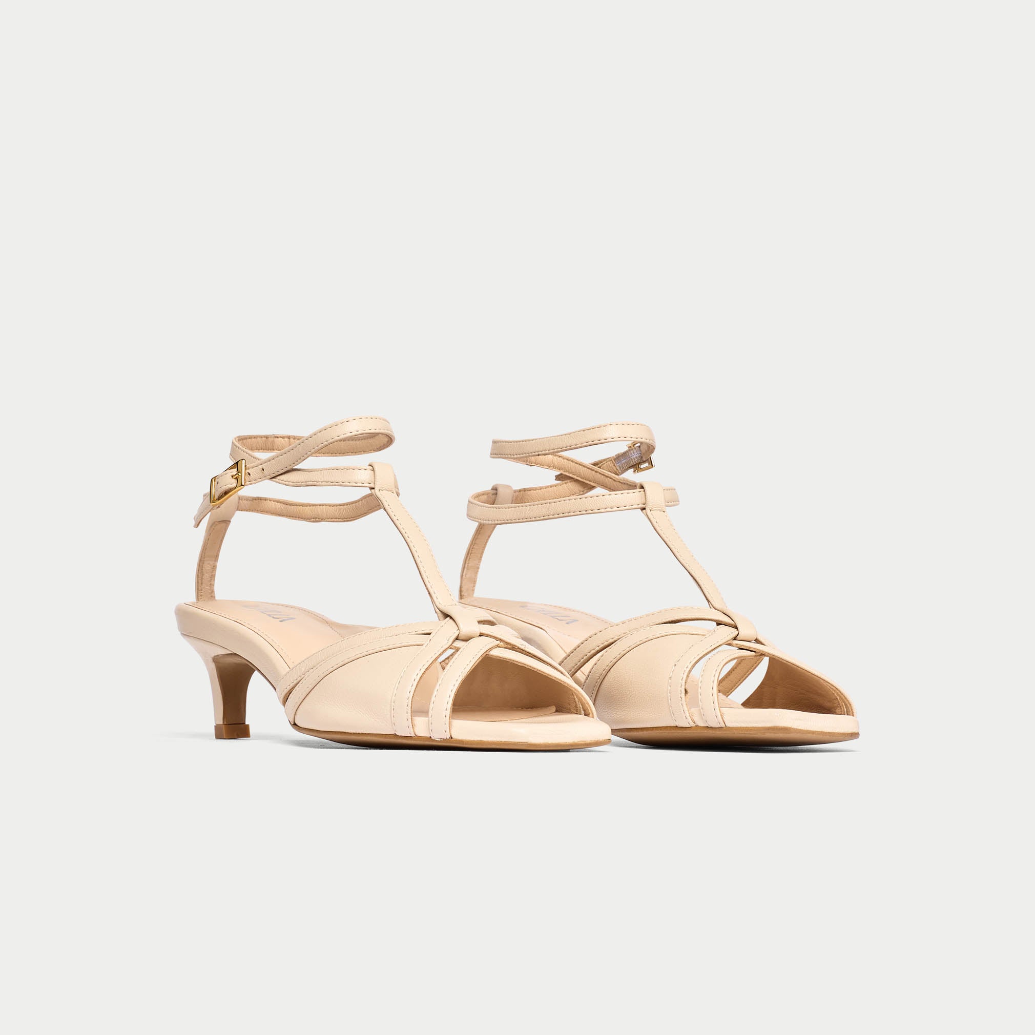 Pair of beige high-heeled sandals on a light gray background